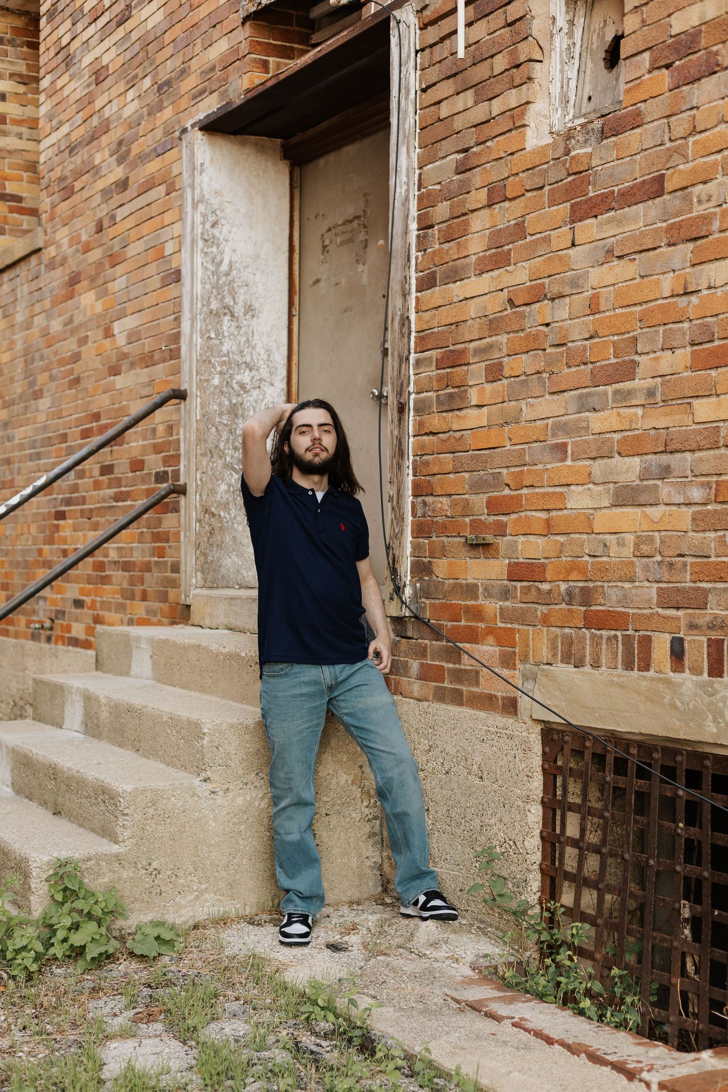 Person resting on concrete steps next to weathered brick building.
