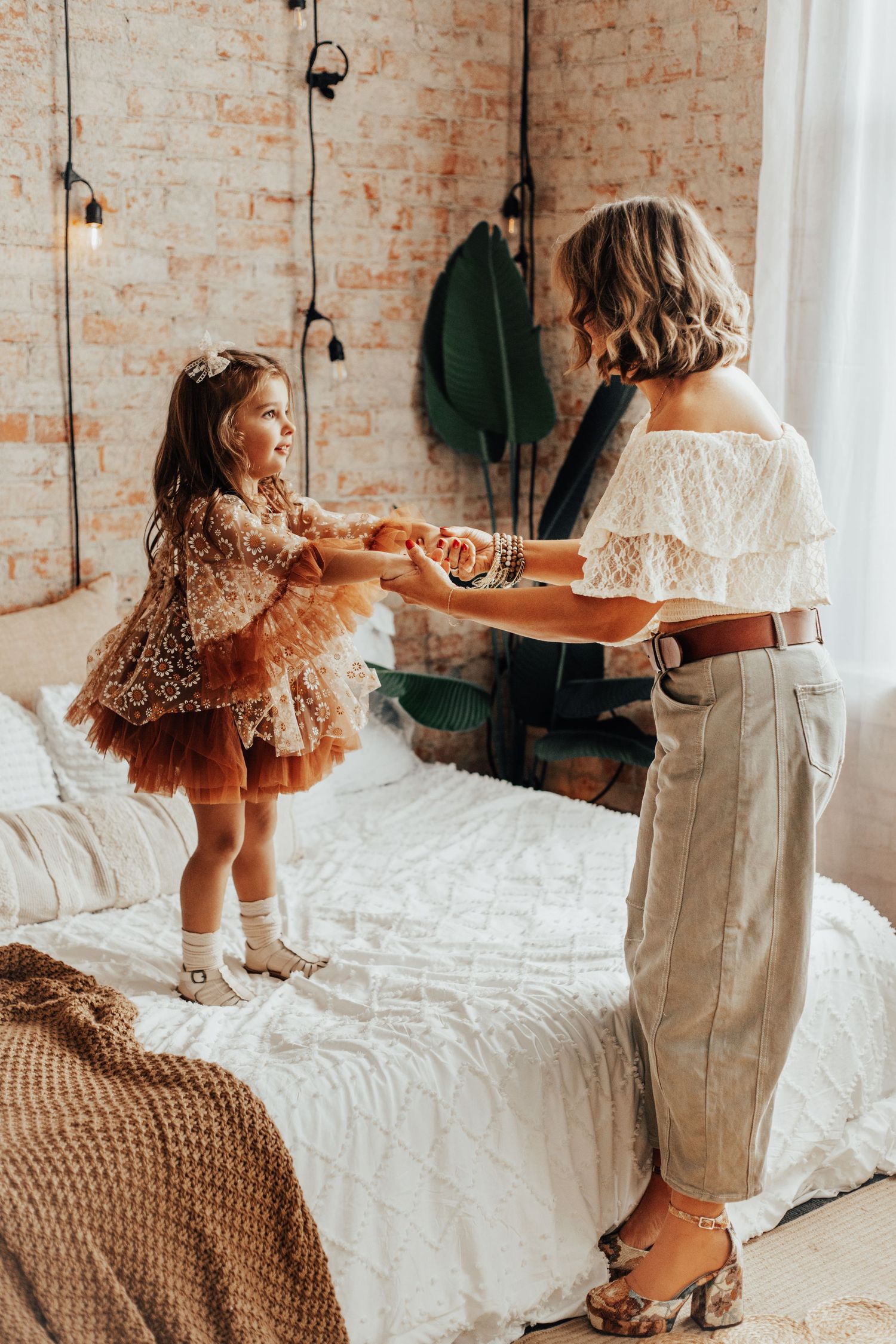 Playful indoor scene with white bedding and exposed brick wall background.