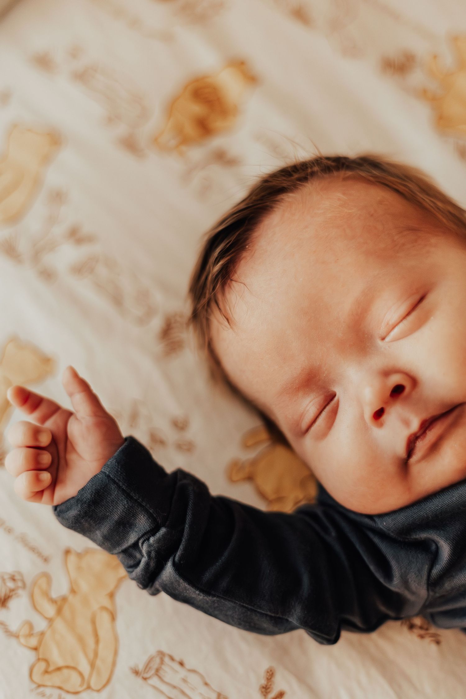 Close-up view of a sleeping infant with dark clothing in warm lighting.