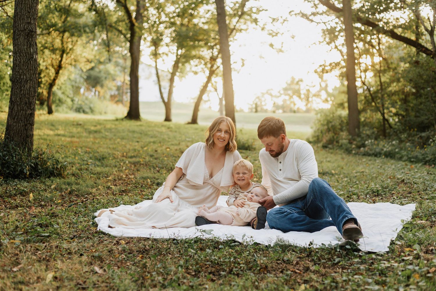 Family enjoying a picnic together on a blanket in a sunlit park.