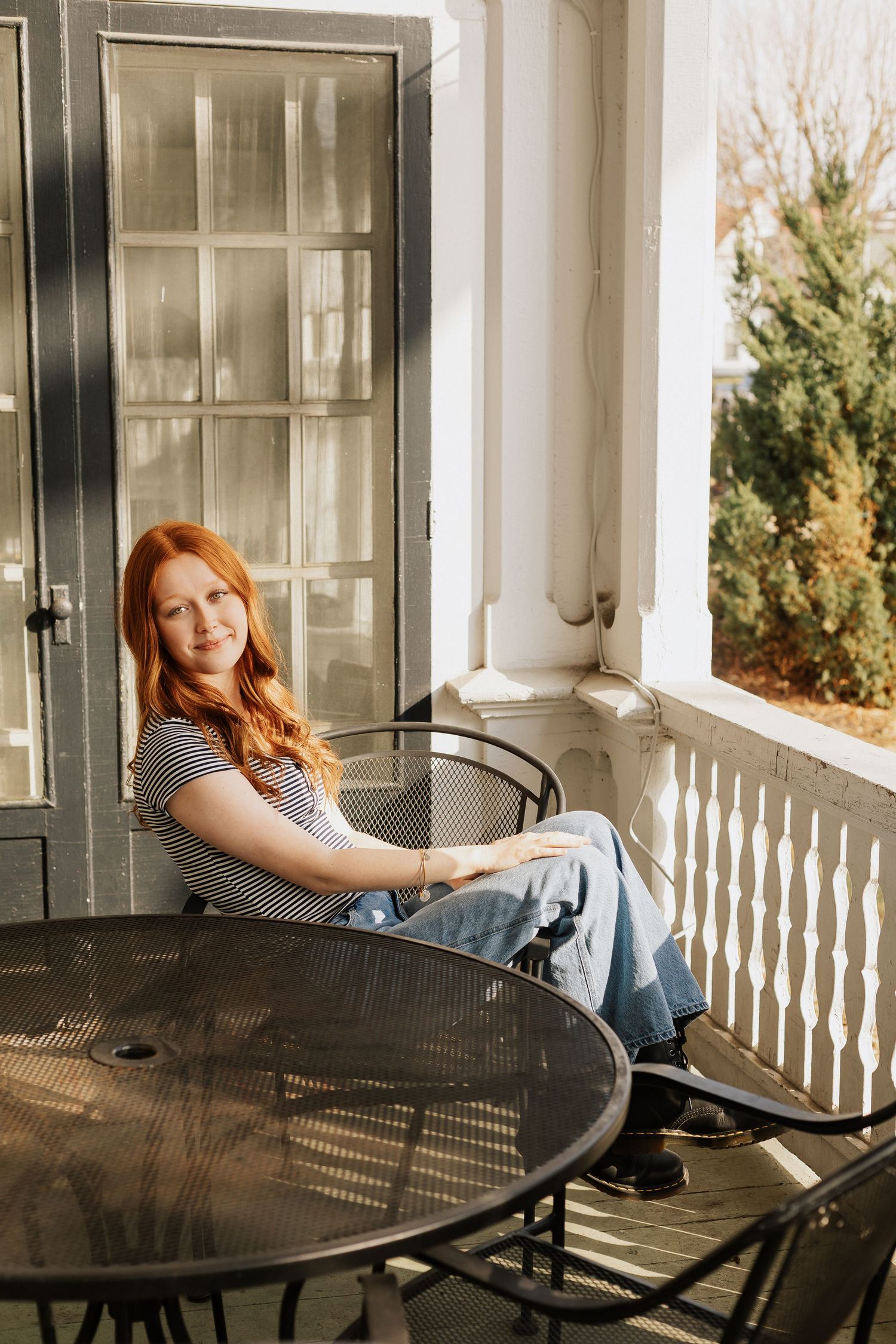 Relaxed poses on a porch with white columns and metal furniture.