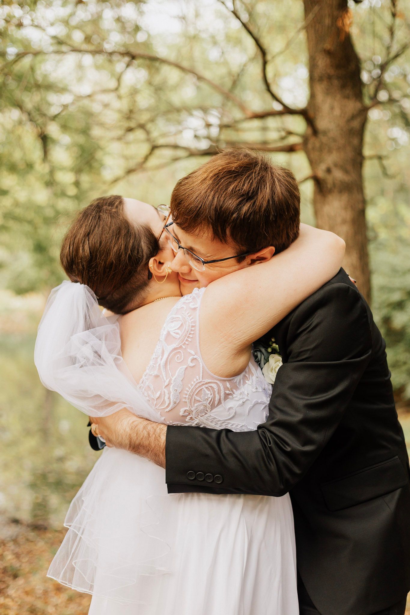 Romantic wedding couple embracing in a wooded setting.