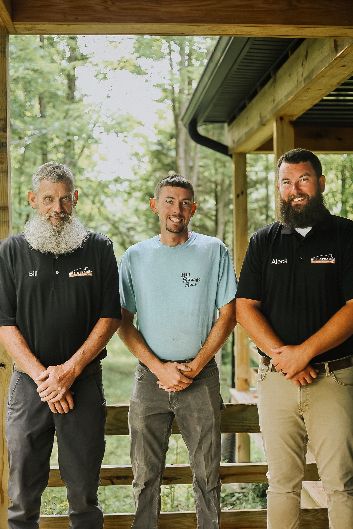Group of workers standing together on a covered wooden porch in casual work attire.