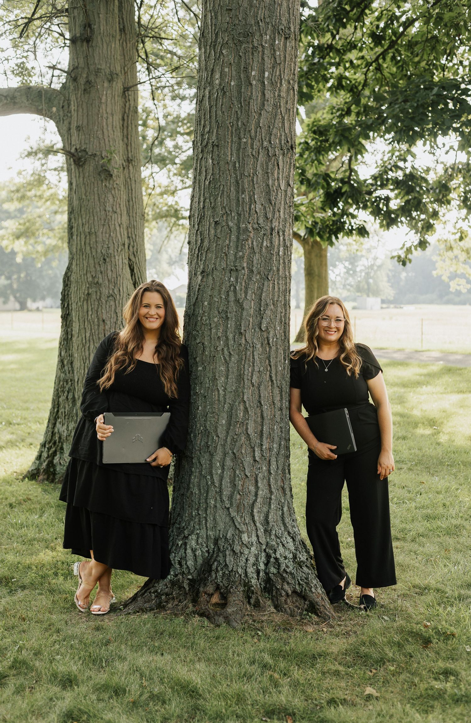 Professional photoshoot near large trees in a park setting.