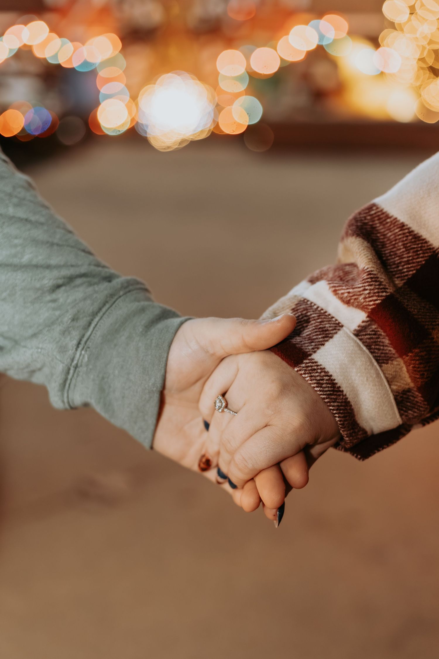 Close-up of two hands clasped together with one wearing a plaid sleeve and the other a sage green sleeve.
