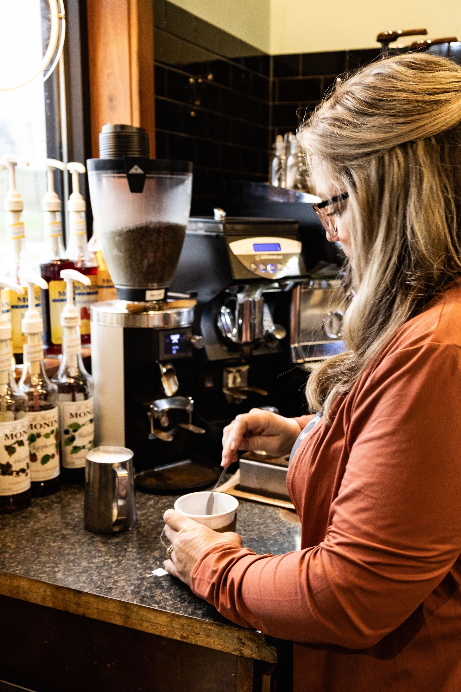 Customer sitting at a coffee bar counter using their phone while waiting for their drink.