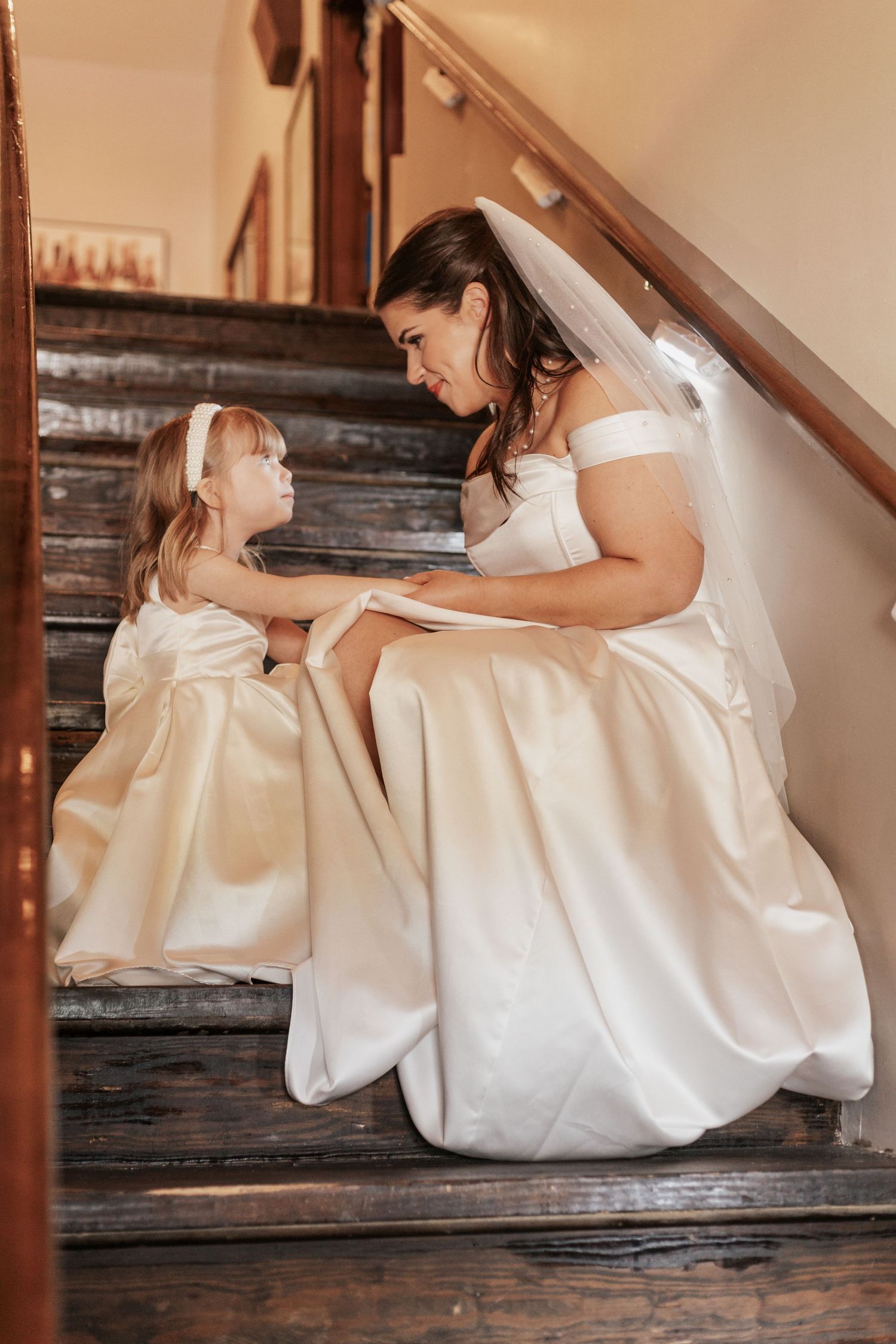 Sweet moment between couple on vintage wooden staircase in wedding attire.