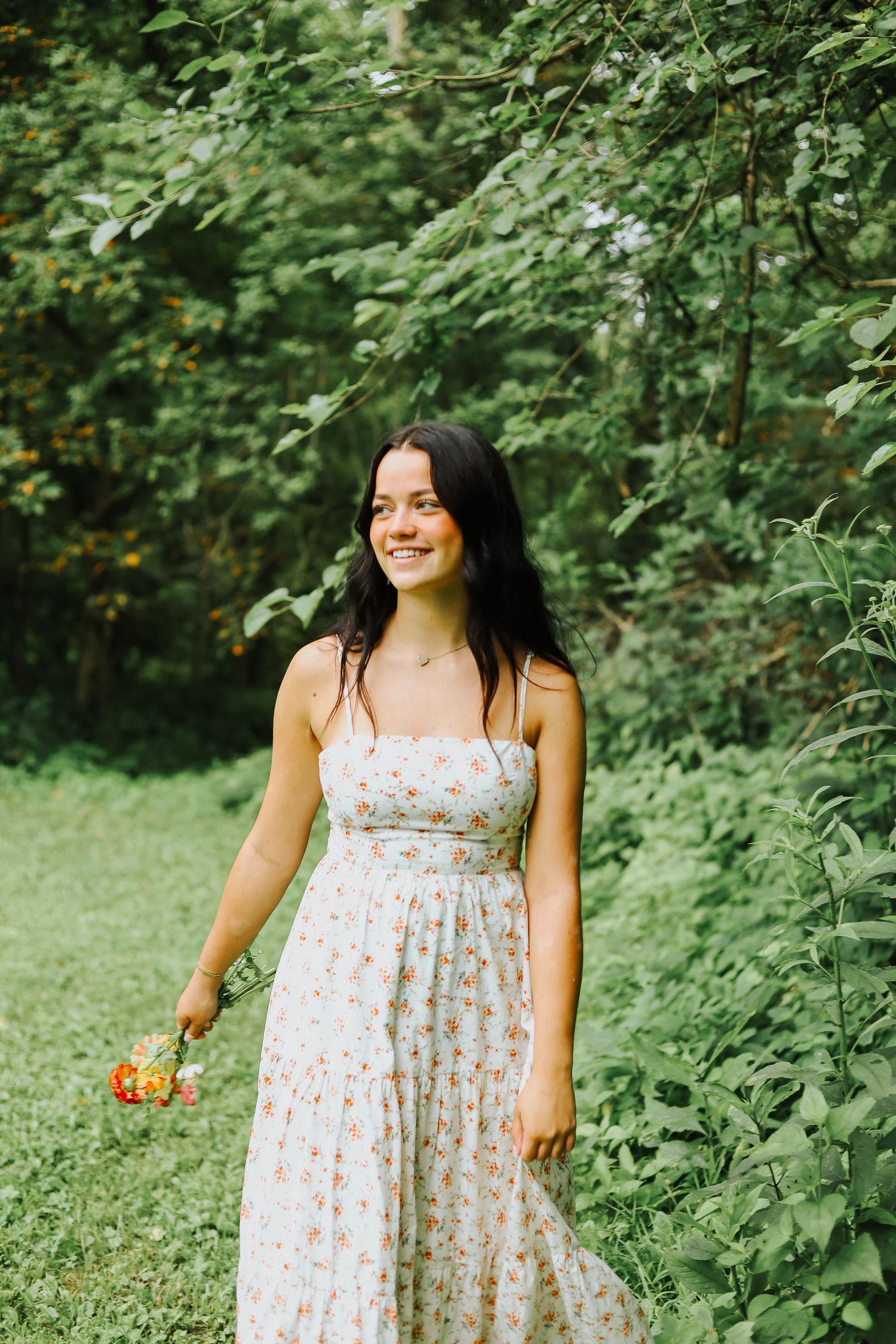 Summer garden photoshoot with someone wearing a floral dress among lush greenery.