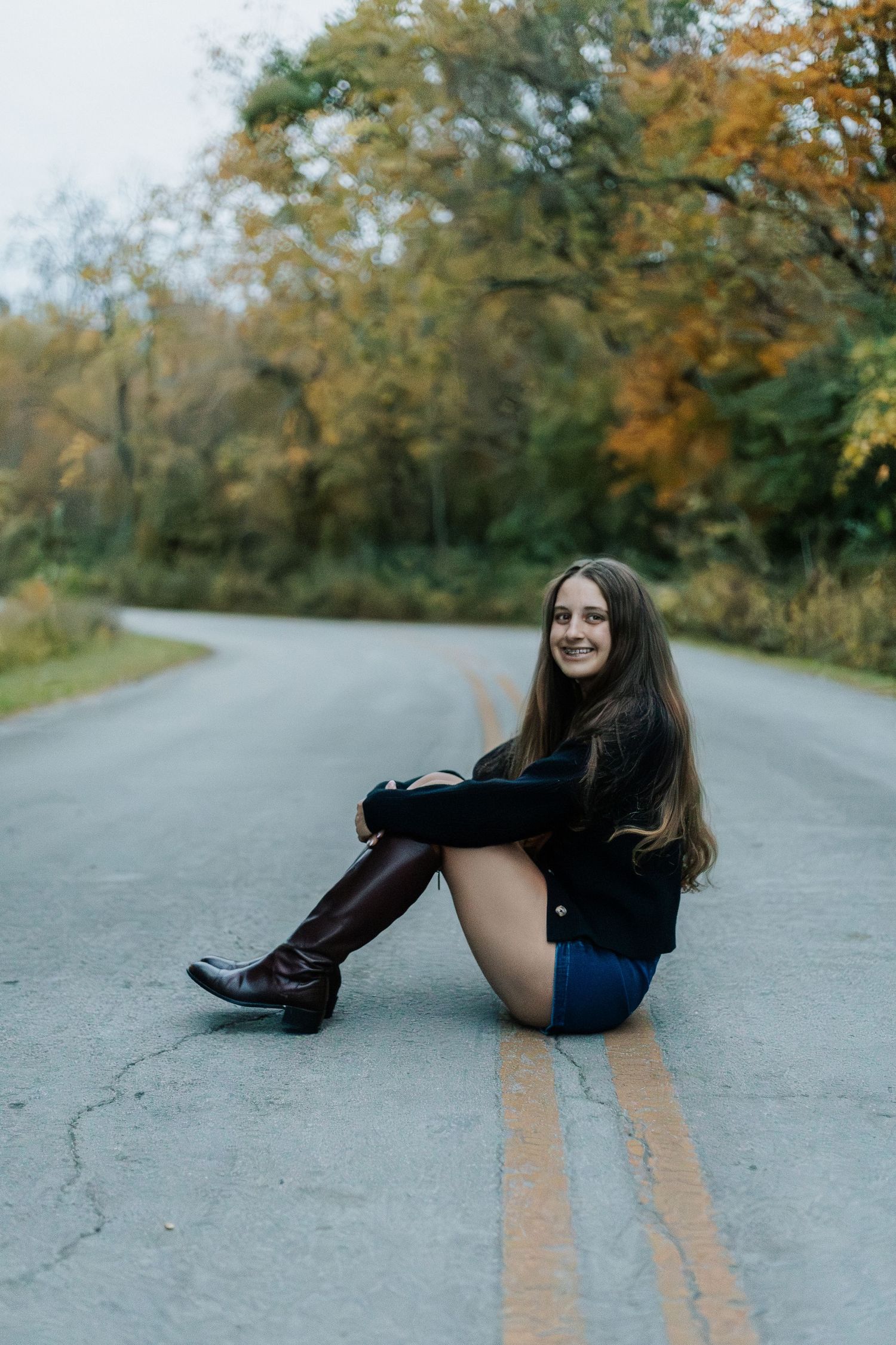 Creative poses on asphalt road with fall foliage in background.