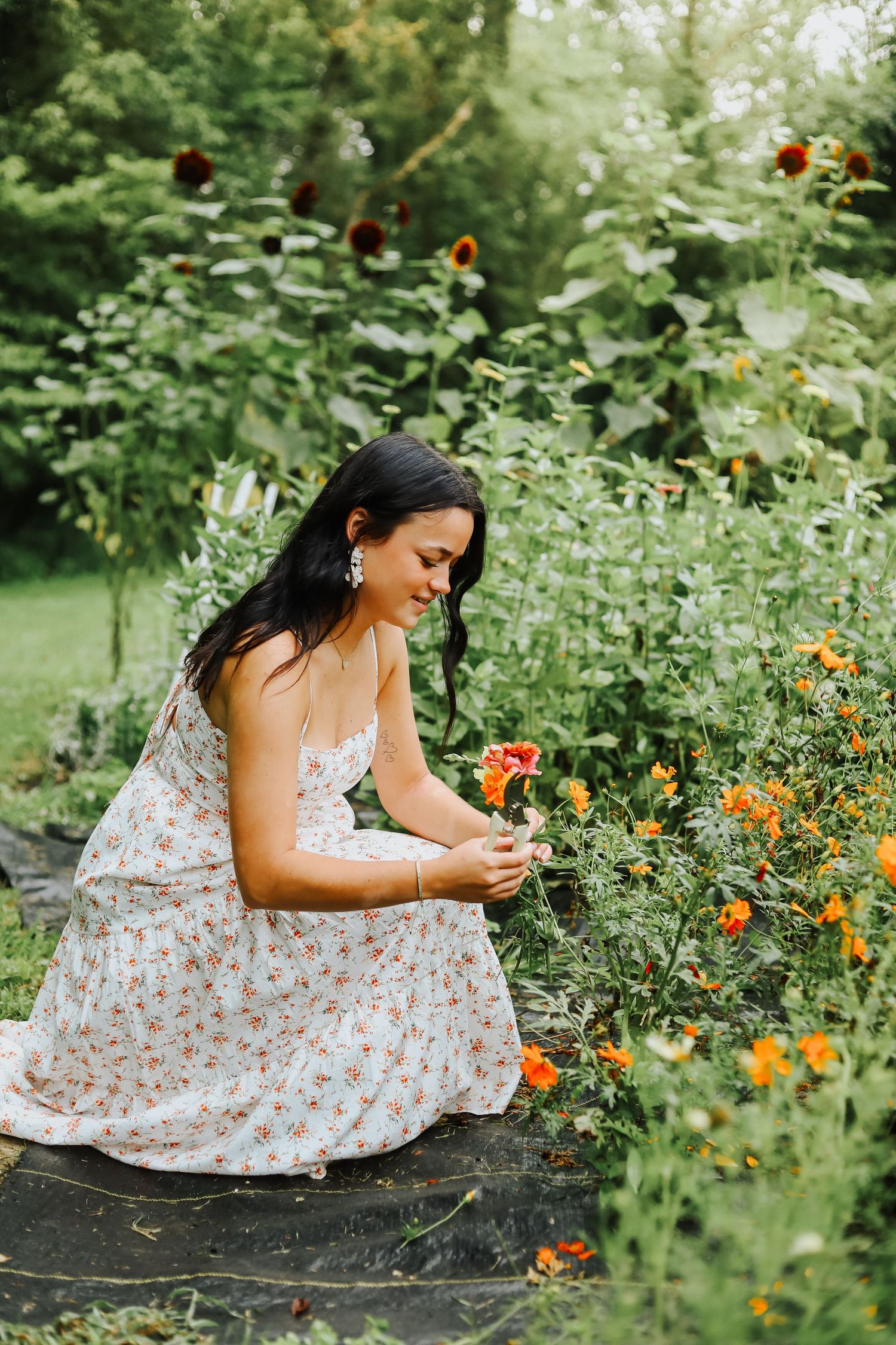 Candid garden photography featuring someone picking flowers among orange and yellow blooms.
