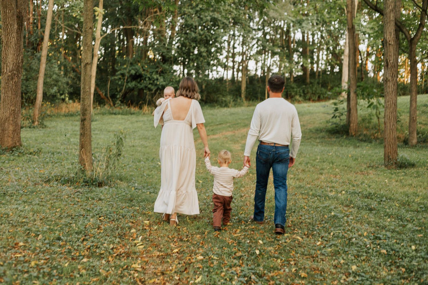 Family walking together through a tree-lined path on a sunny afternoon.