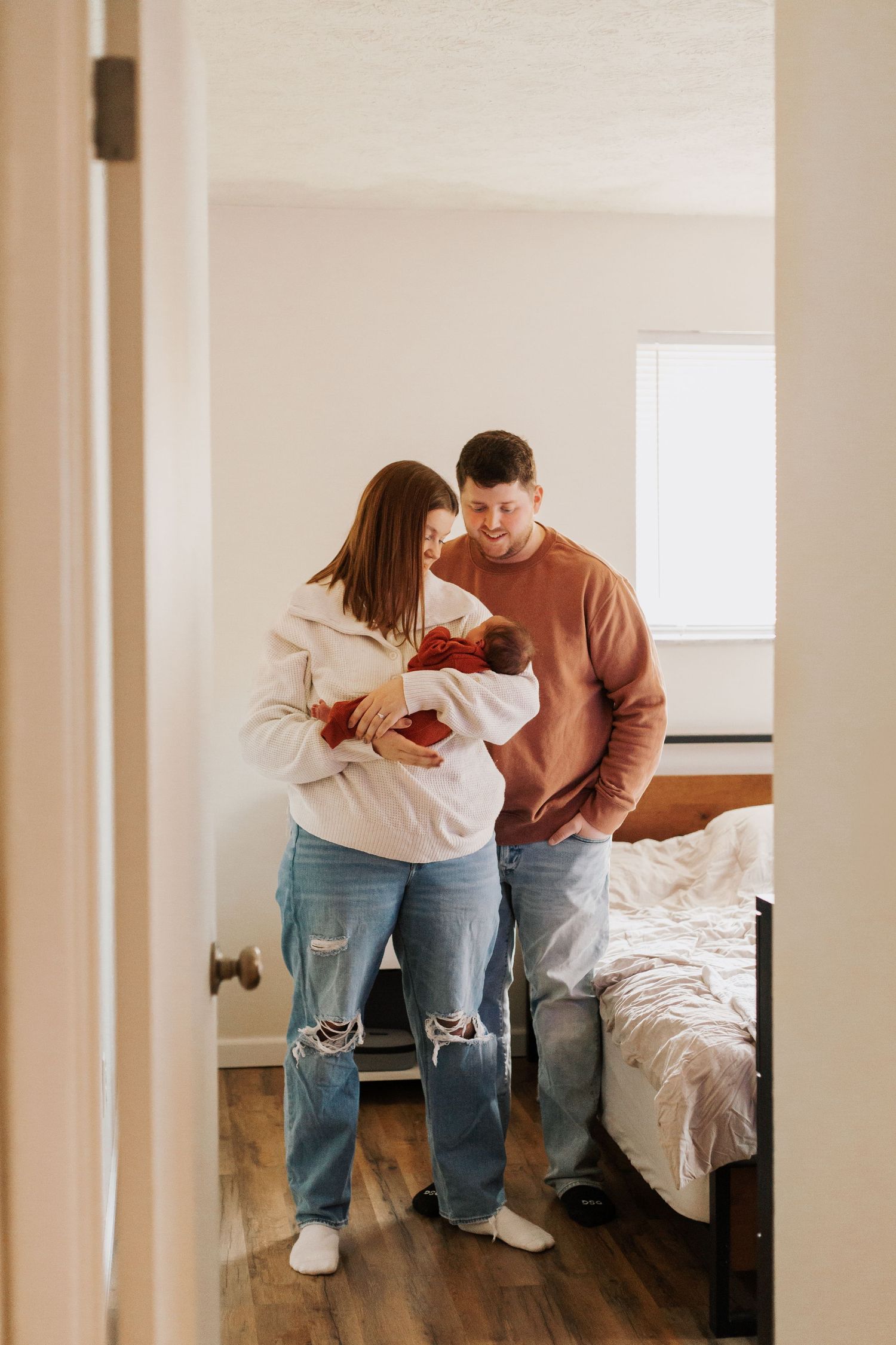 Parents sharing playful moments with their baby in a bright bedroom.