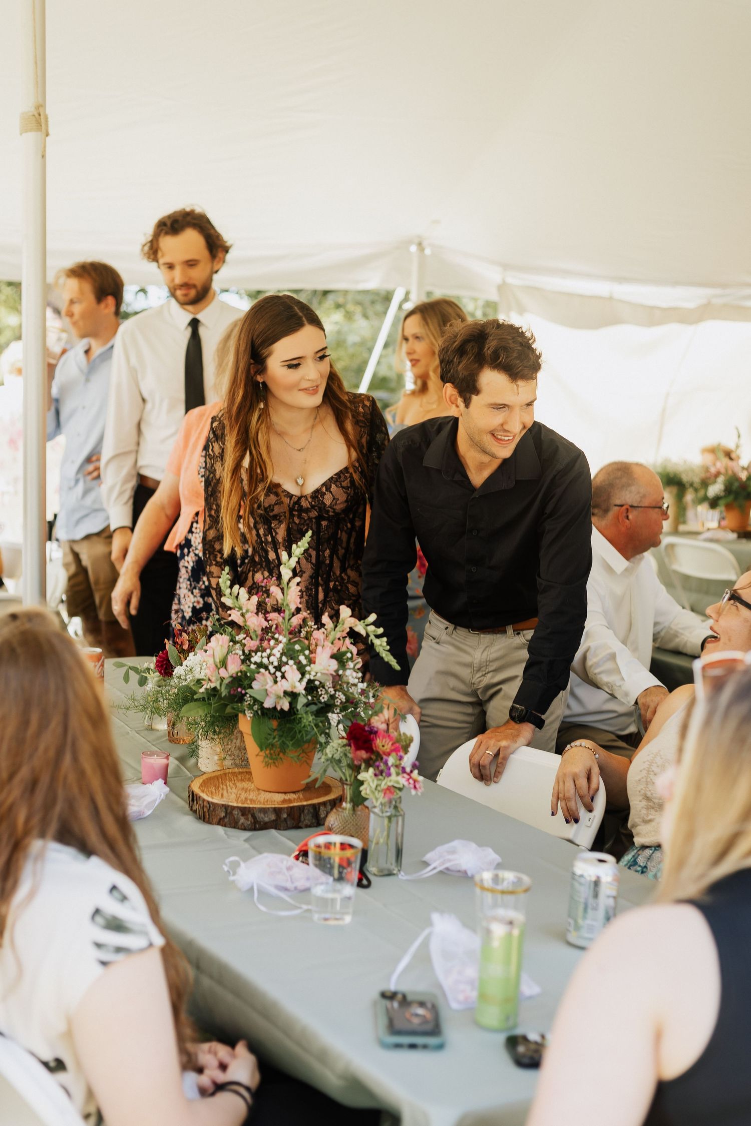 Wedding reception guests gathered under a white tent enjoying a meal at decorated tables.