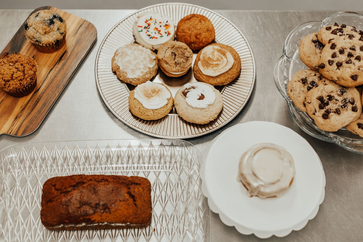 Various baked goods including cookies and bread loaves displayed on white plates and wooden boards.