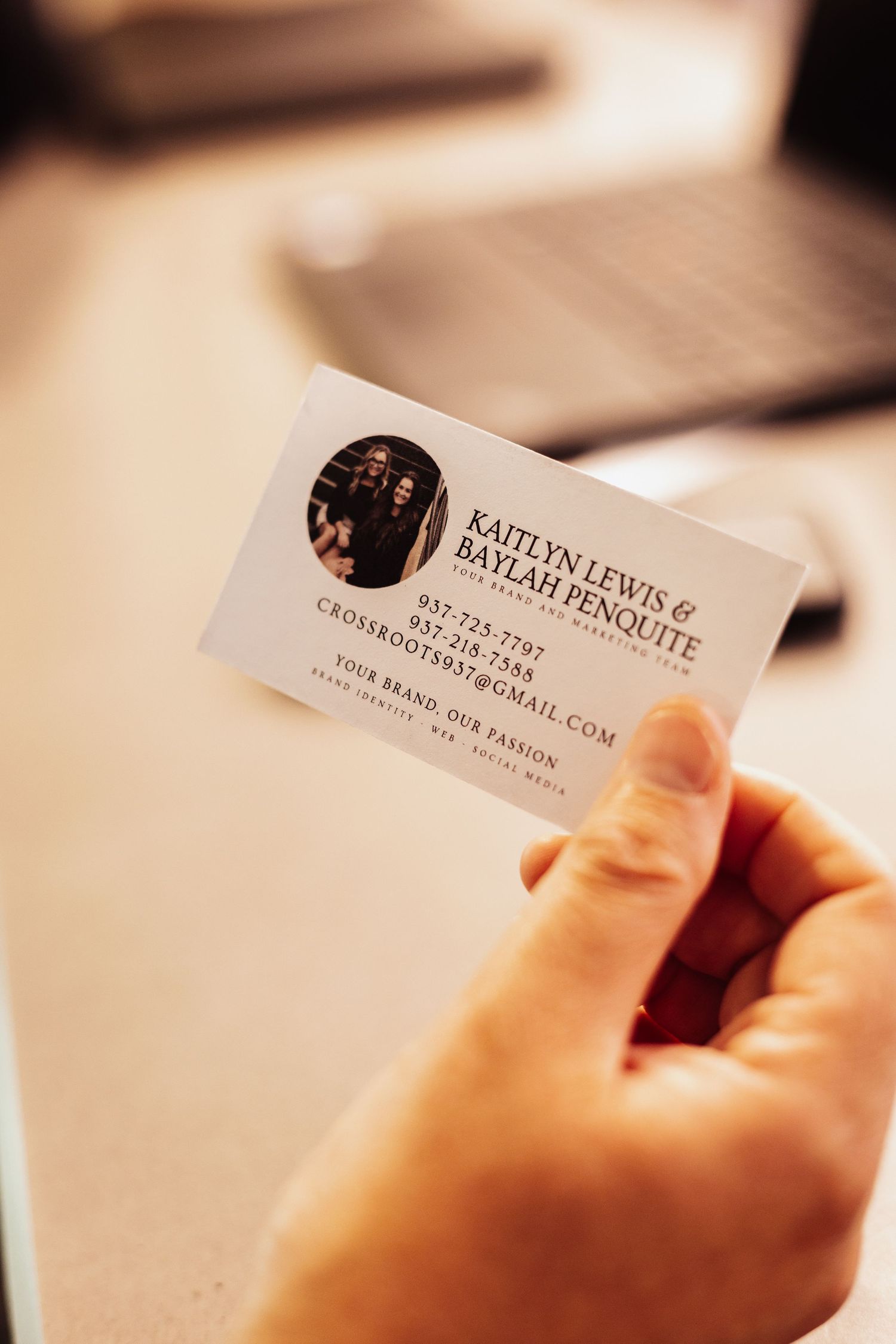 Close-up view of hands holding business cards with contact information.