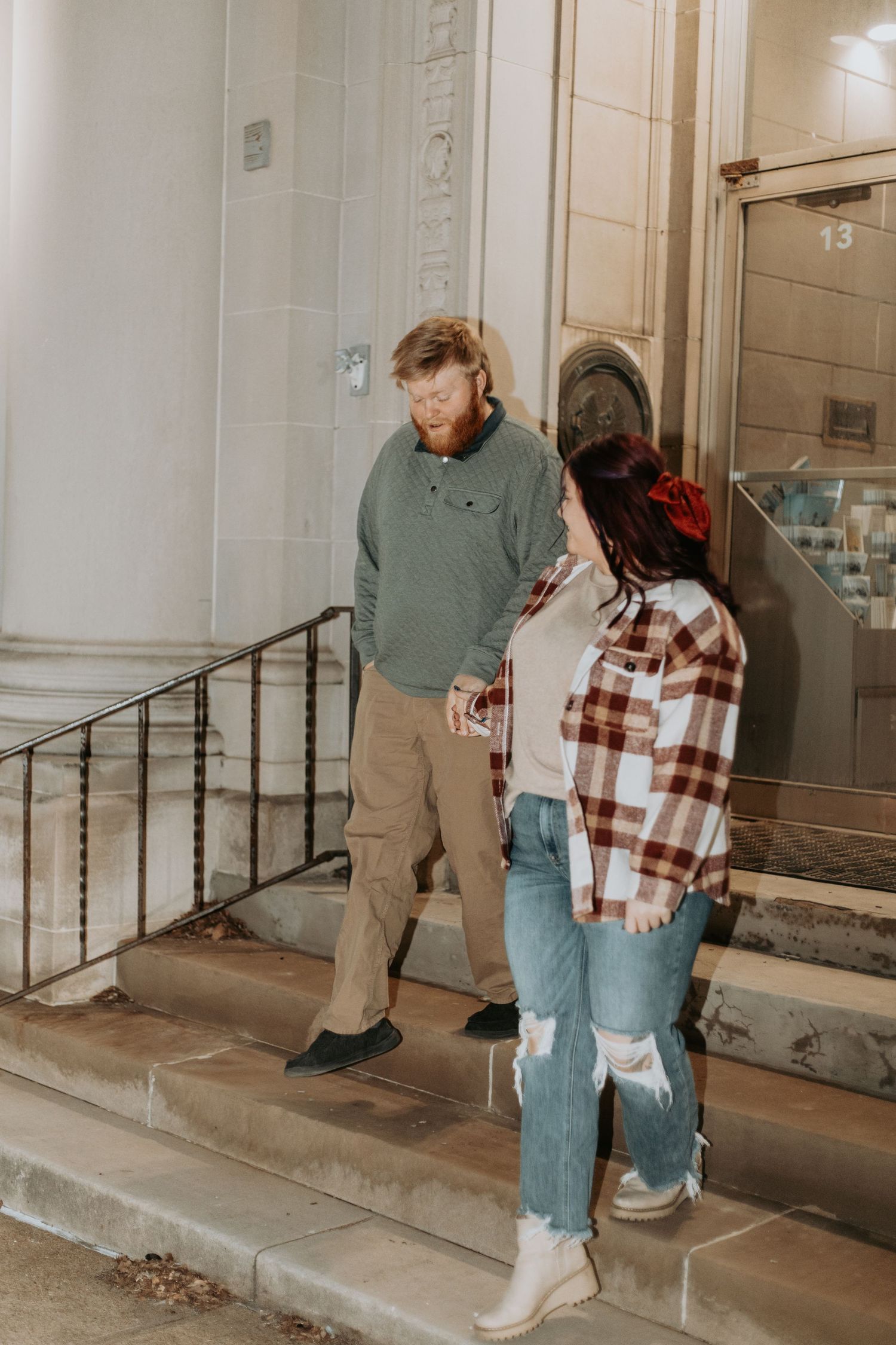 A couple stands together on stone steps outside a building.