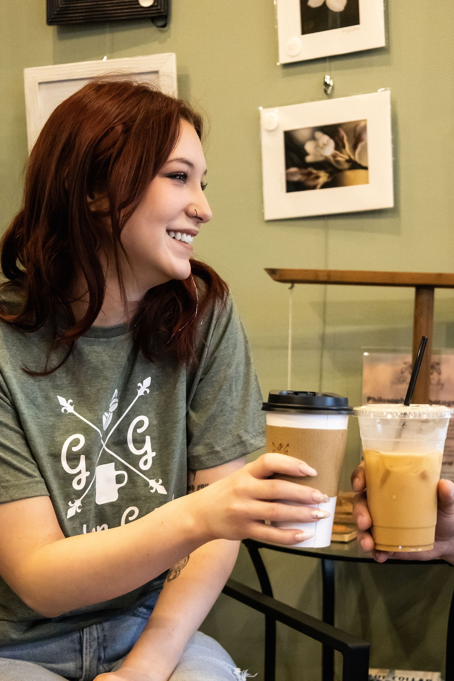 Person enjoying iced coffee drinks at casual cafe with artwork on walls.