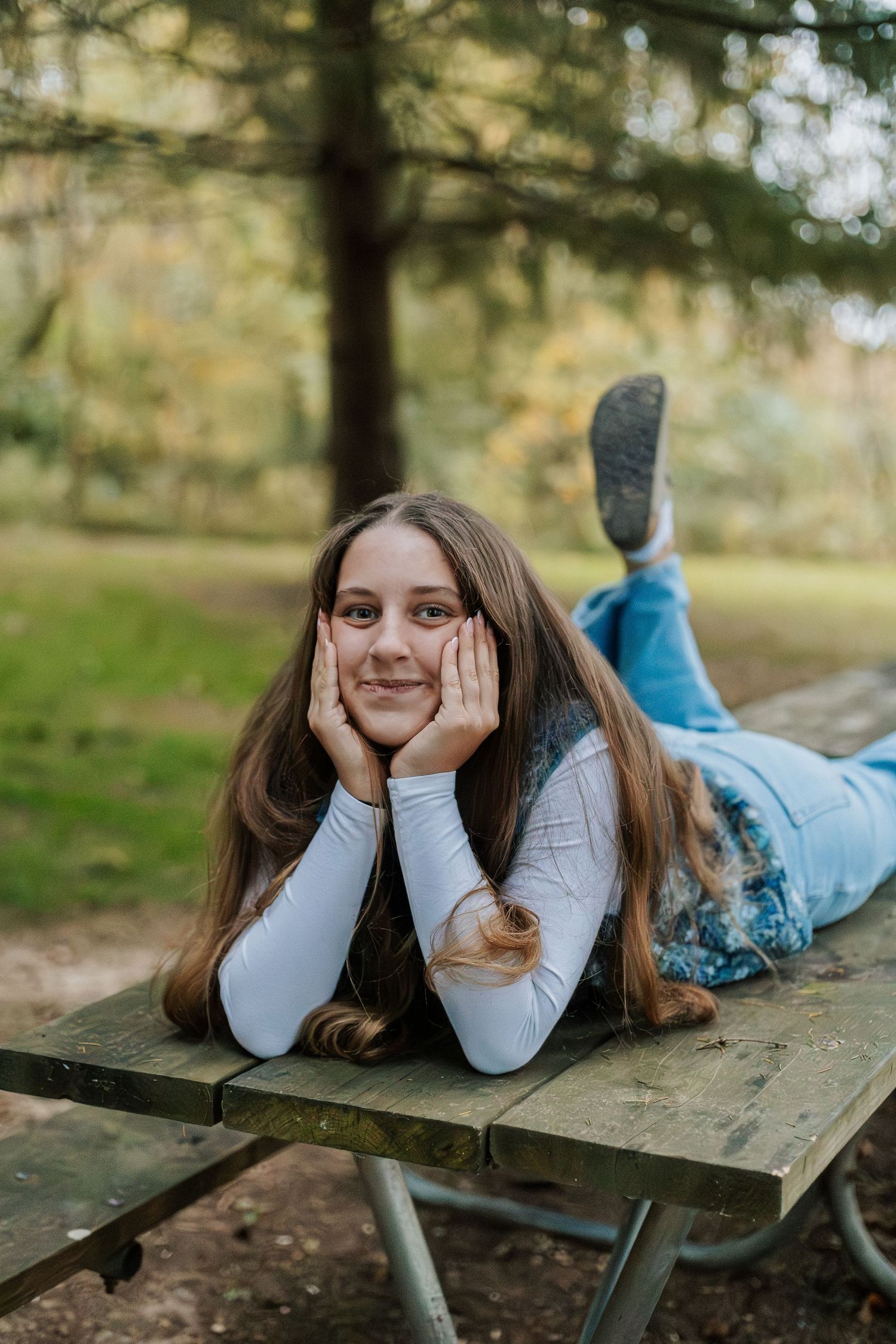 Relaxed portrait session on wooden picnic table surrounded by autumn scenery.