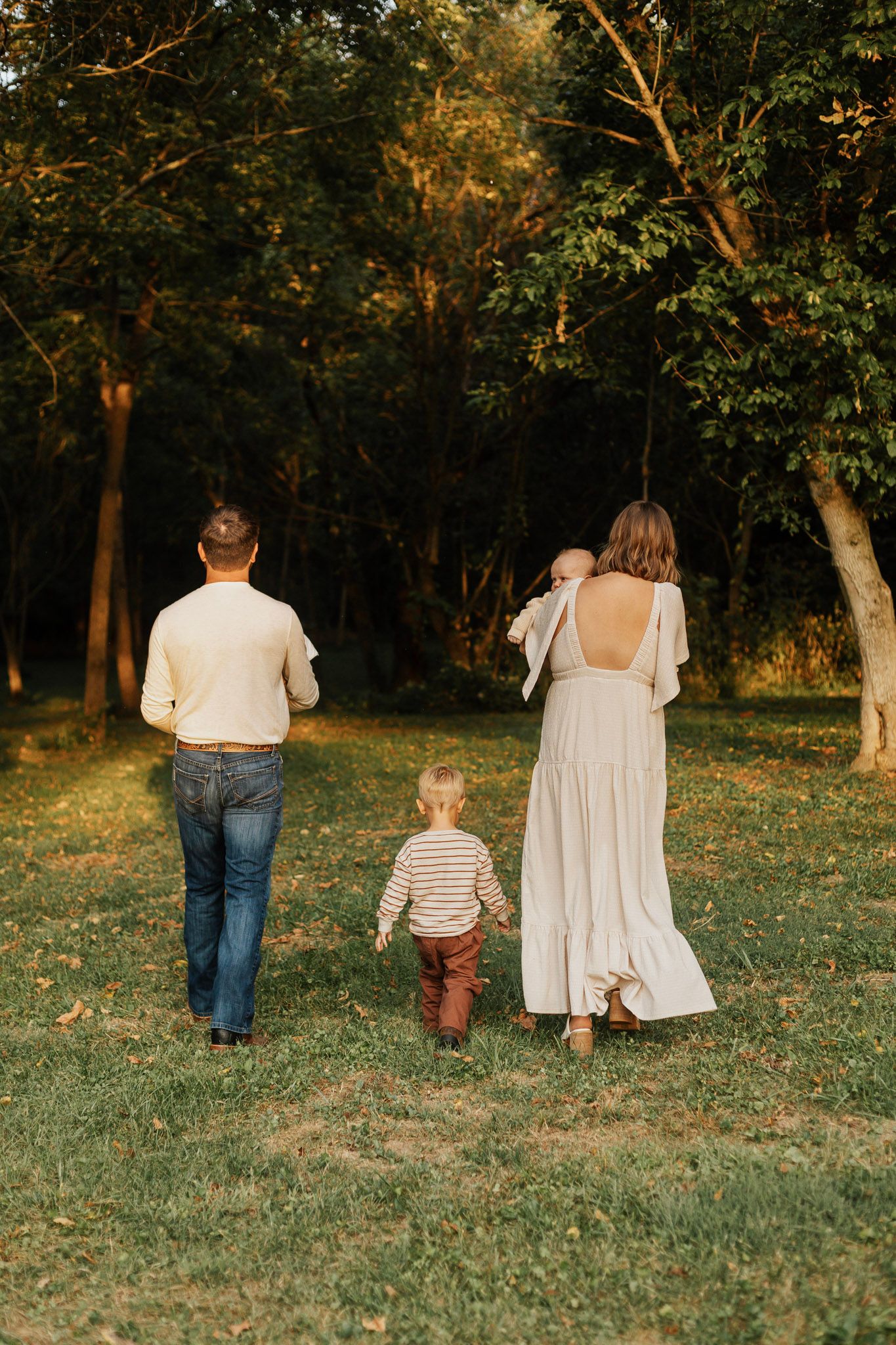 Family walking together through a grassy field at sunset.