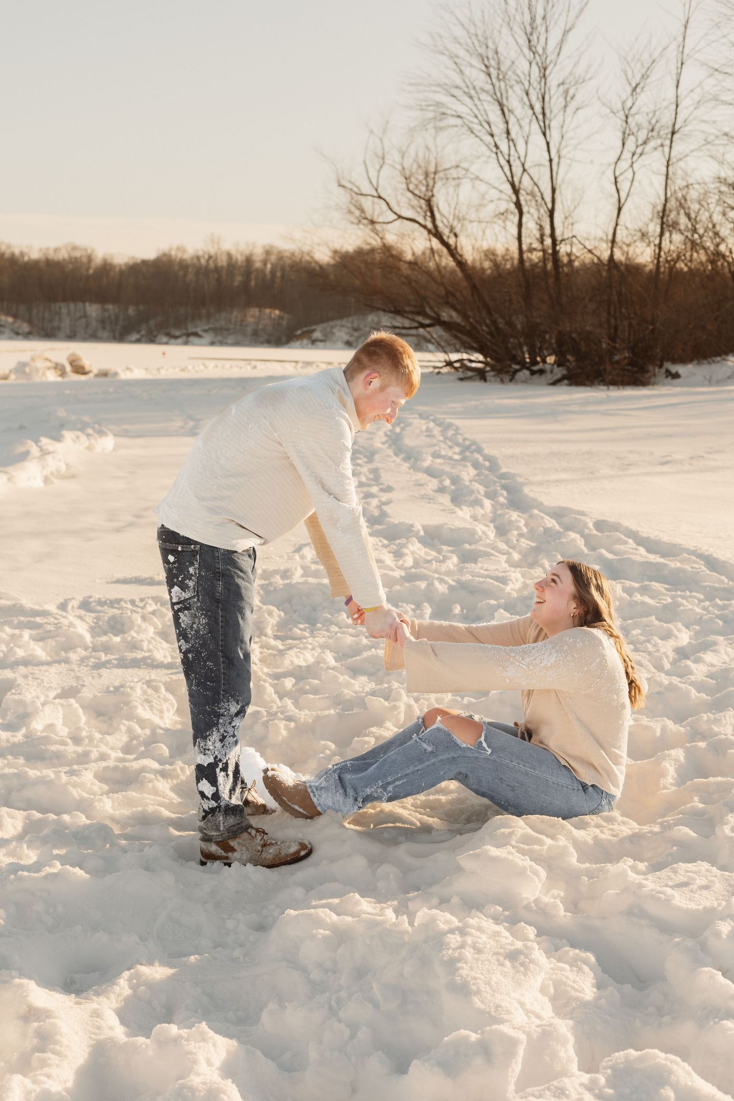 A couple plays in the snow during a winter photoshoot.