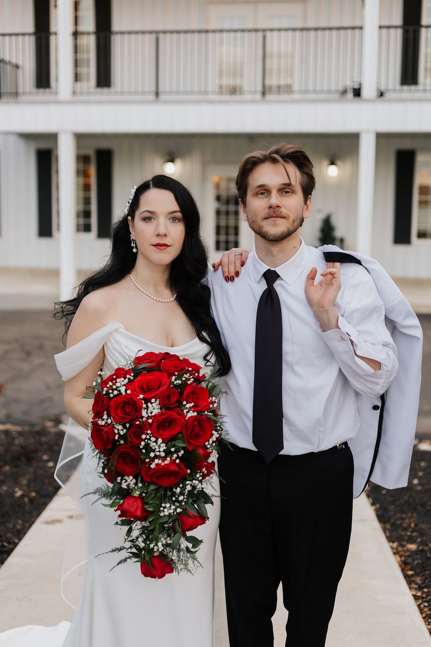 Wedding portraits featuring a stunning red rose bouquet and classic black and white formal wear.