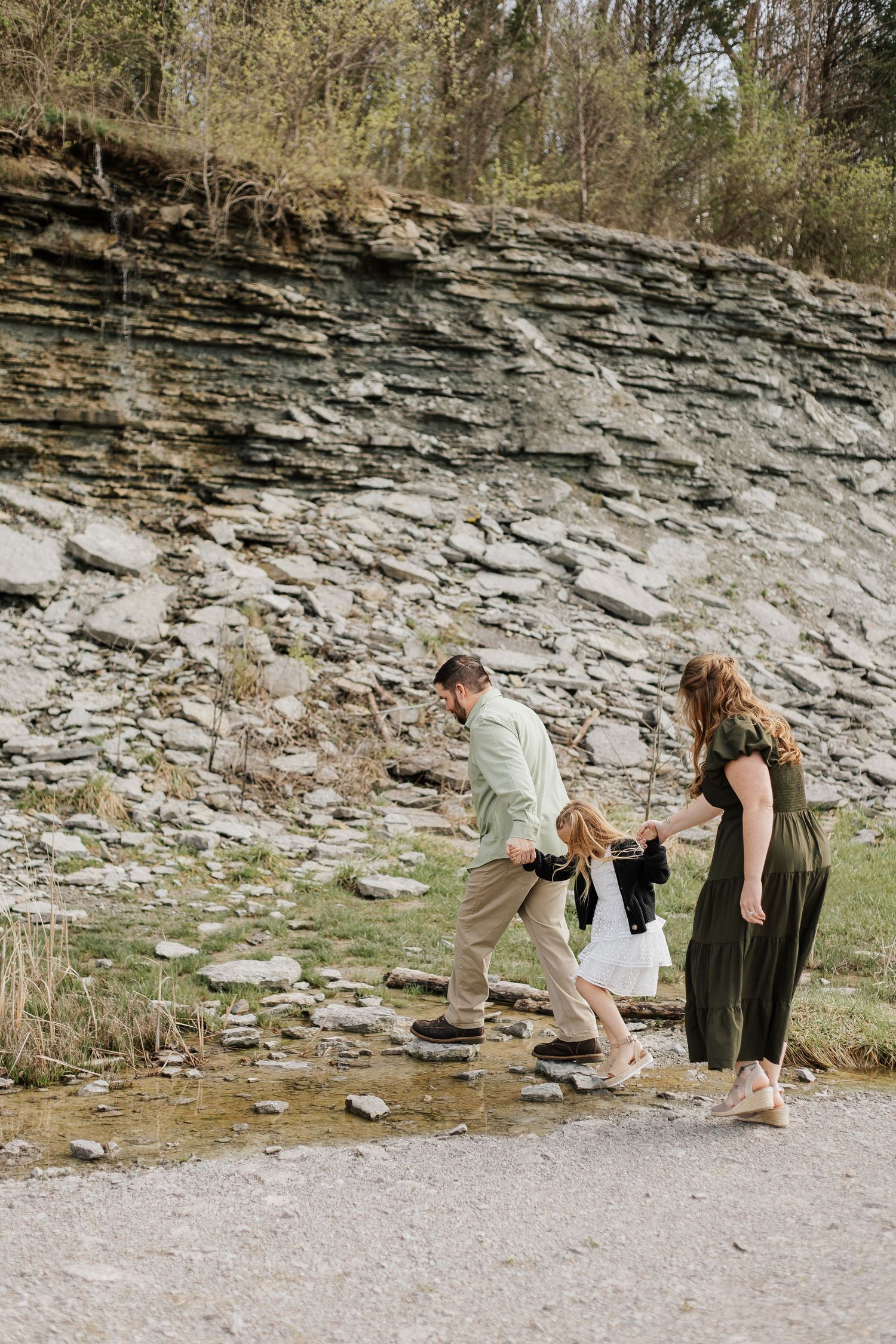 Family walking along rocky cliff path during outdoor adventure.