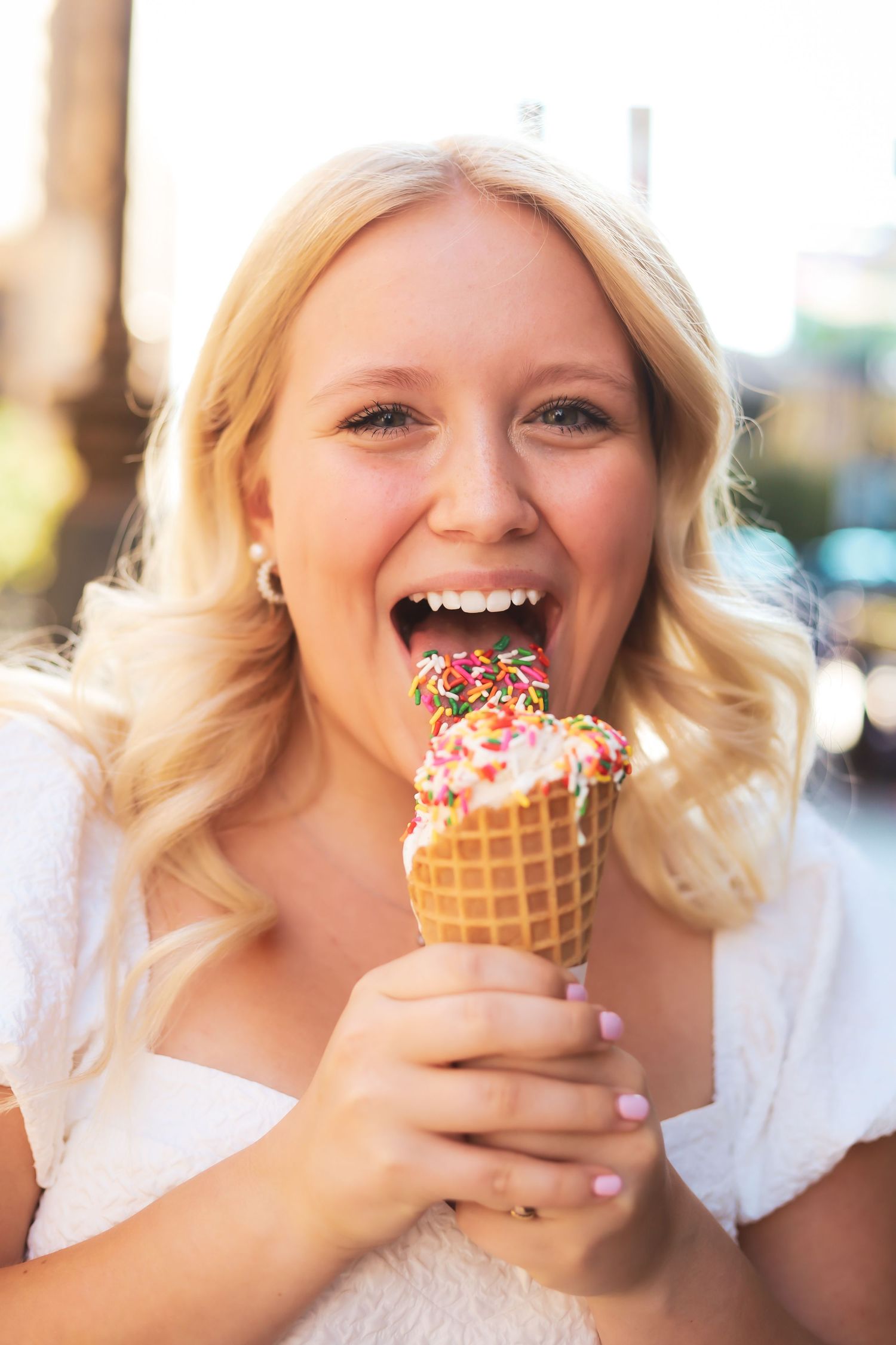 Person enjoying ice cream cone with sprinkles in natural sunlight.