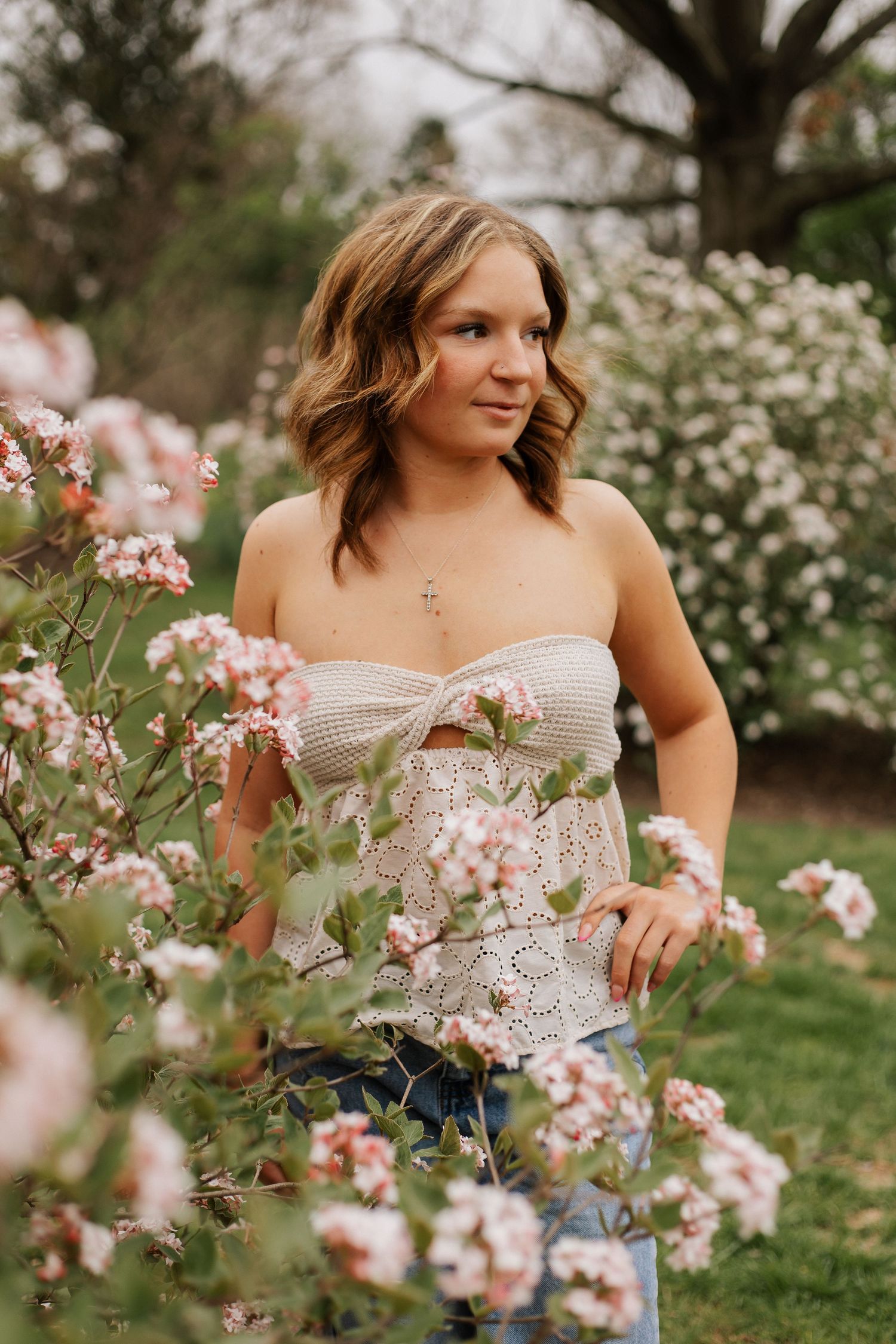 Spring portrait session among blooming pink flowers and garden foliage.