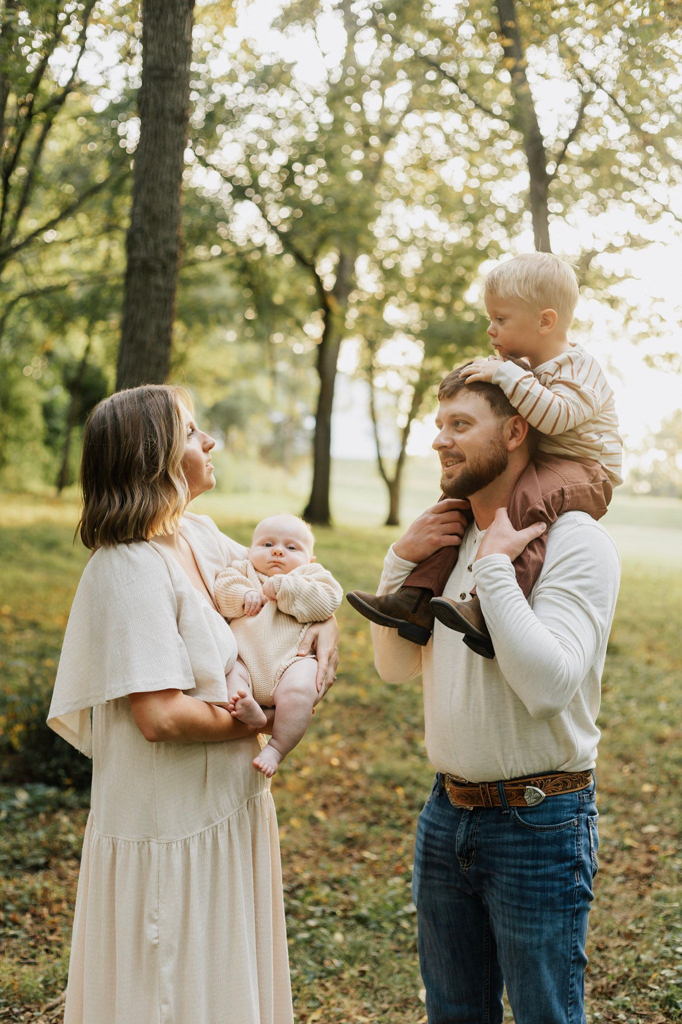 Family sharing tender moments together in a sunlit park setting.