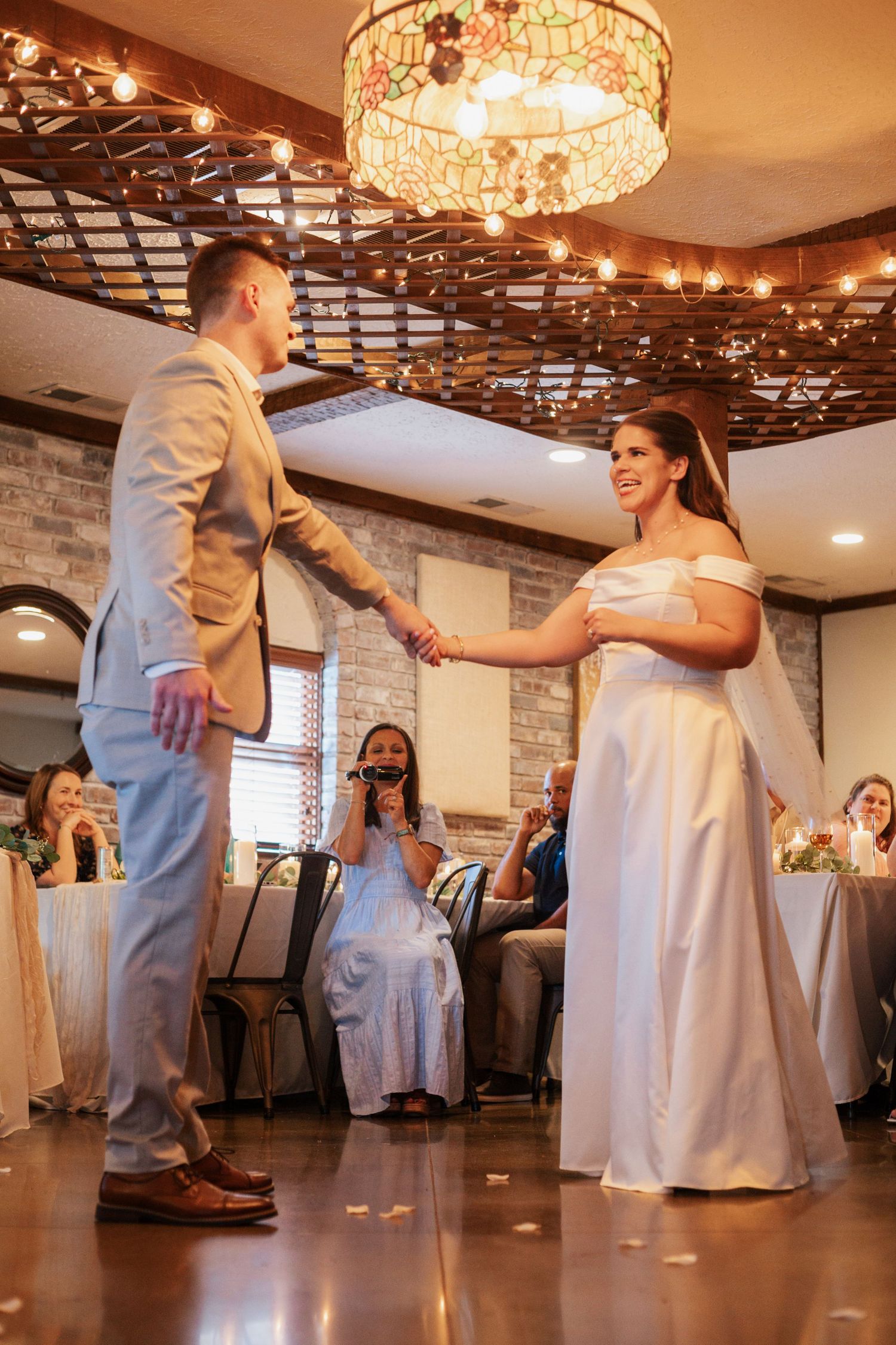 Wedding couple dancing sequence in an elegant reception hall with crystal chandeliers overhead.