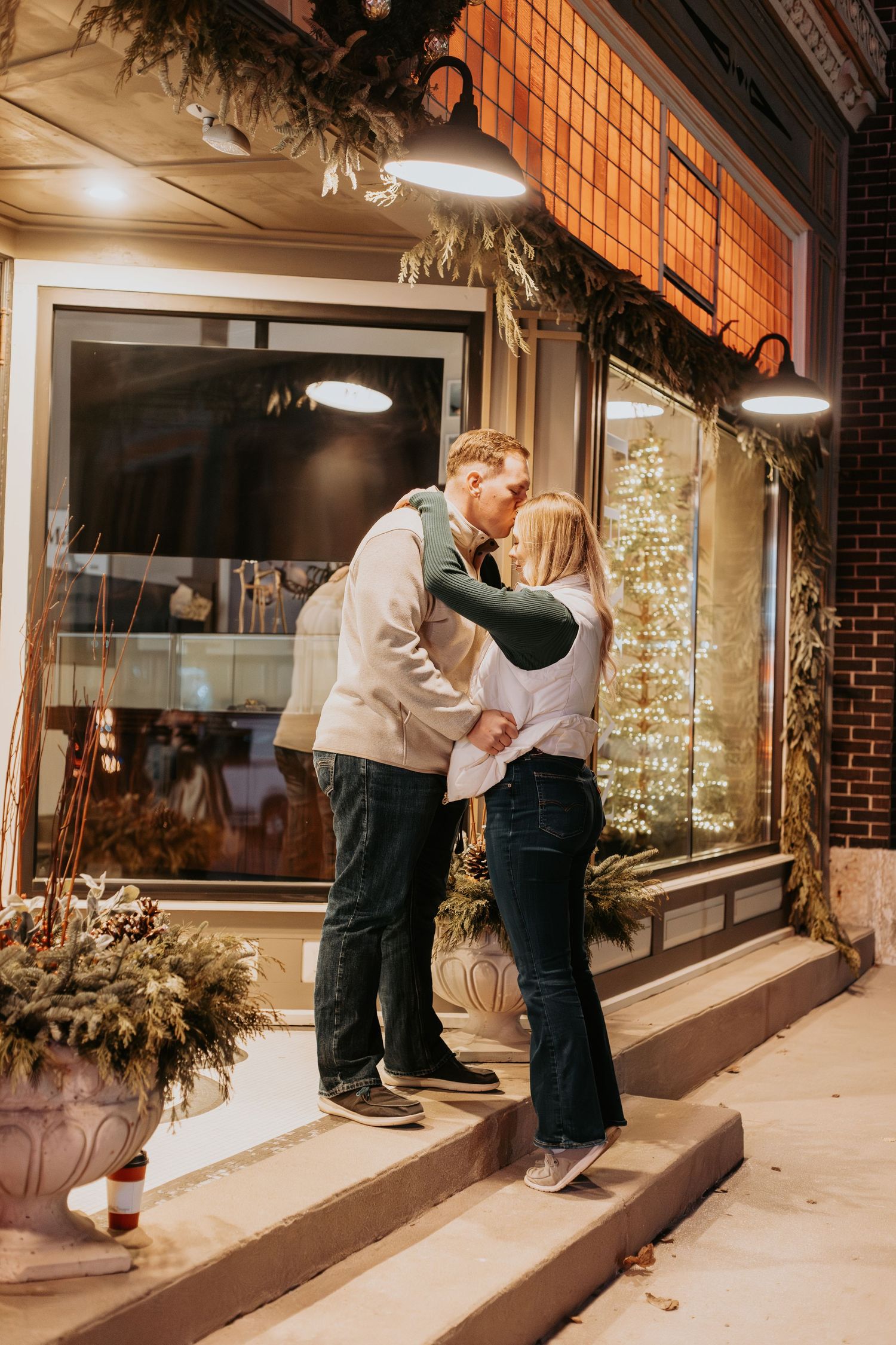 Romantic evening scene outside a decorated storefront with holiday greenery.