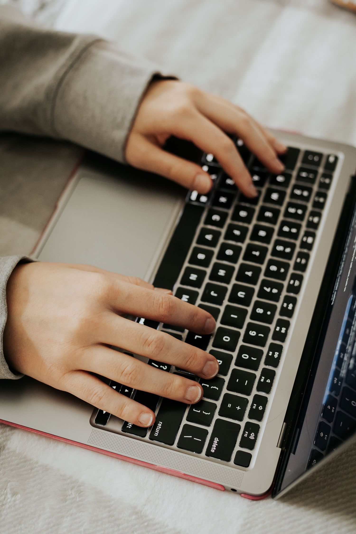 Hands typing on a MacBook keyboard in natural lighting.