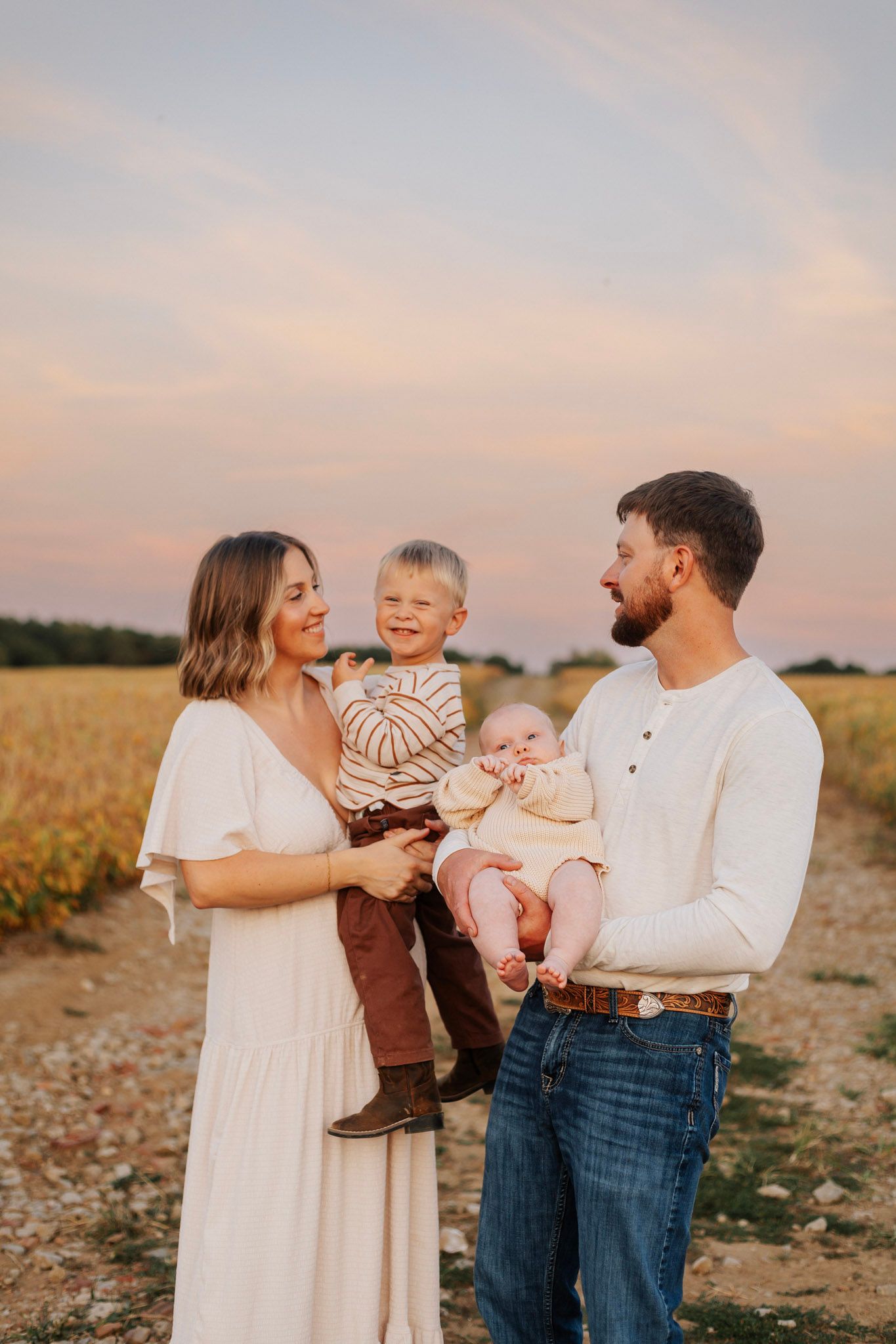 A family shares joyful moments together in a field during golden hour sunset.