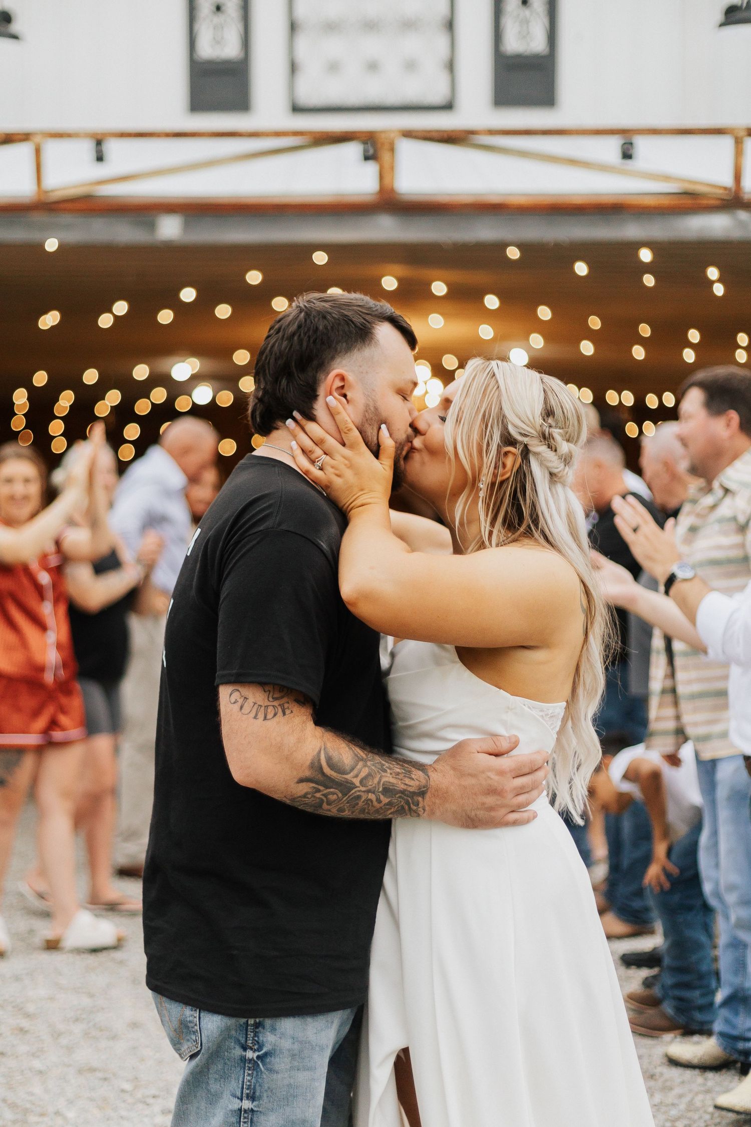 Couple dancing together under string lights at an outdoor reception venue.