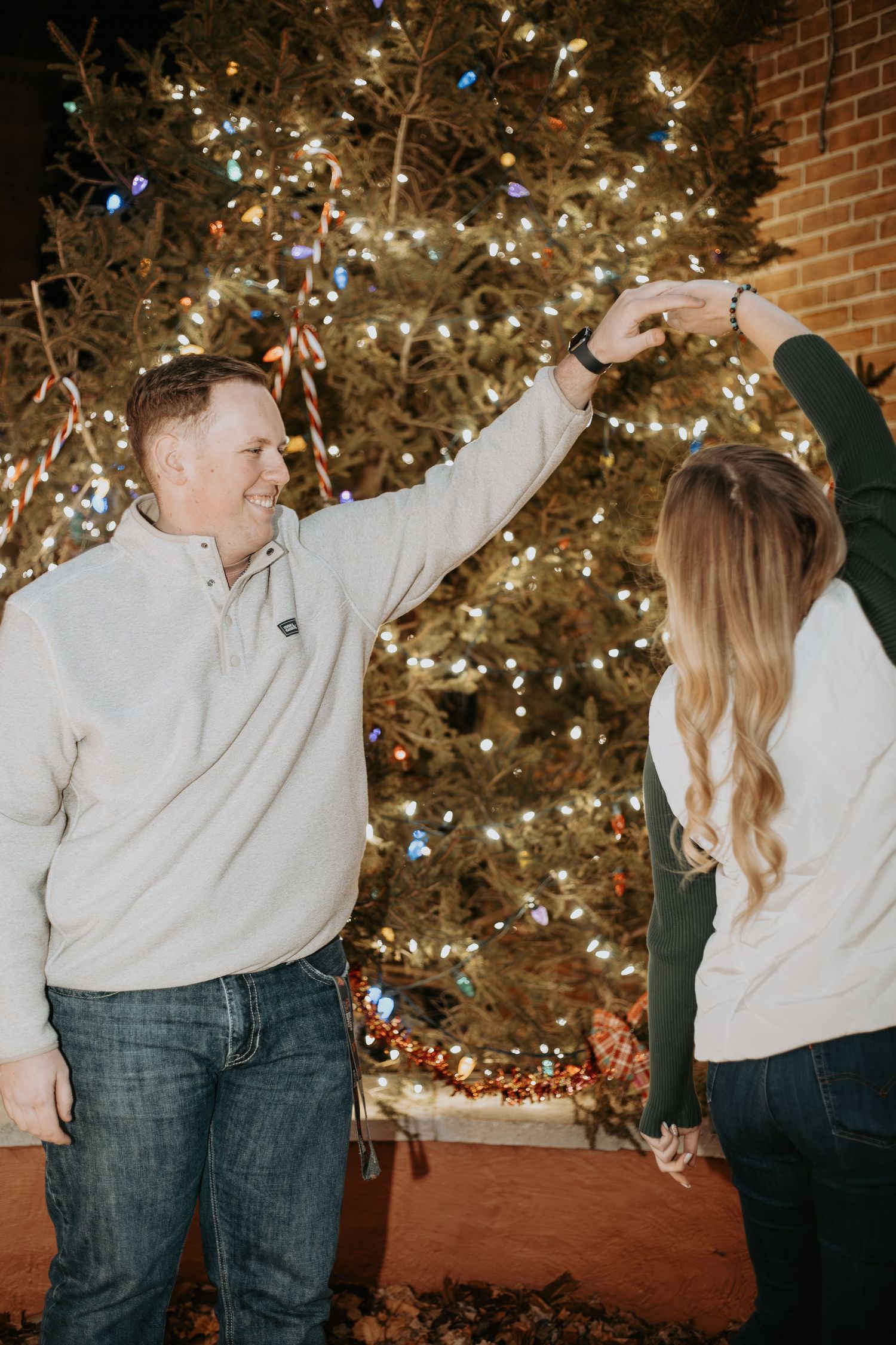 Joyful moment in front of a sparkling Christmas tree at night.