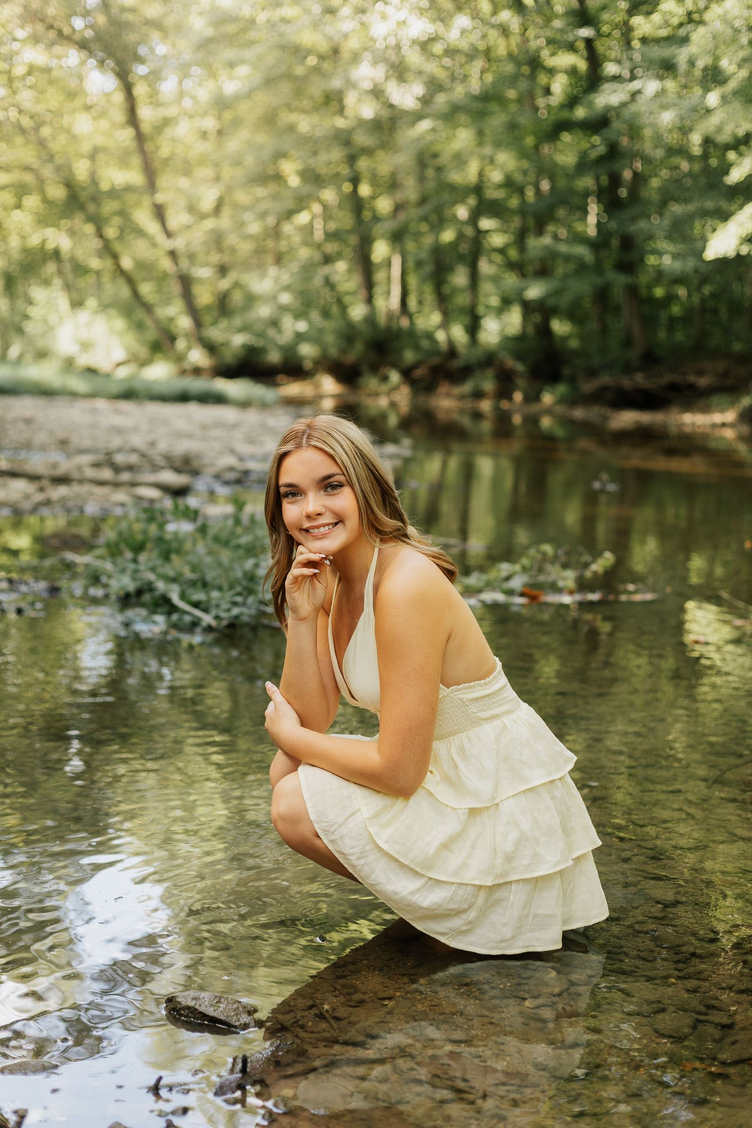 An artistic creek-side portrait session with crystal clear water and natural stone elements.