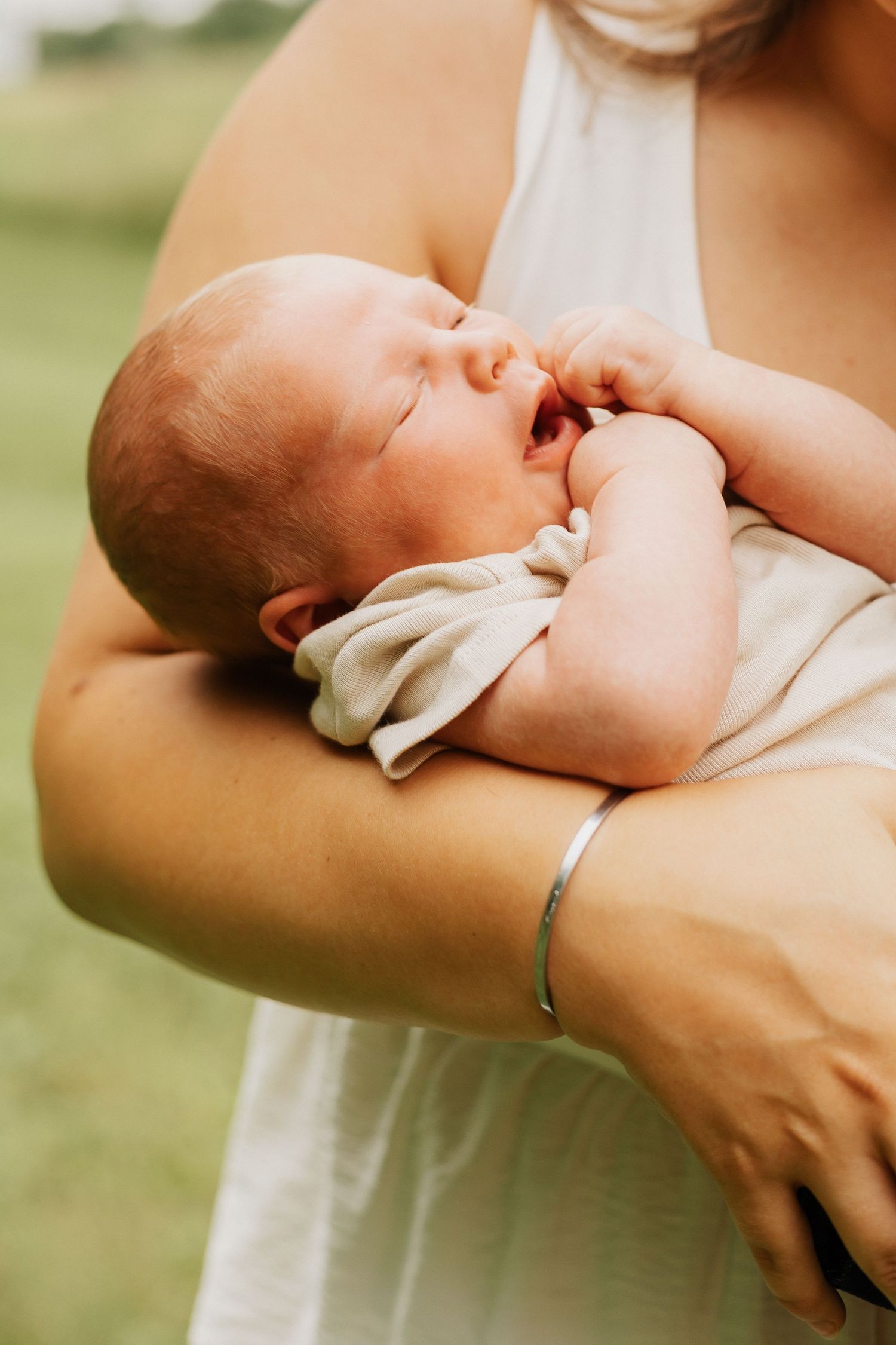 Close-up of baby being cradled in arms with gentle natural lighting.