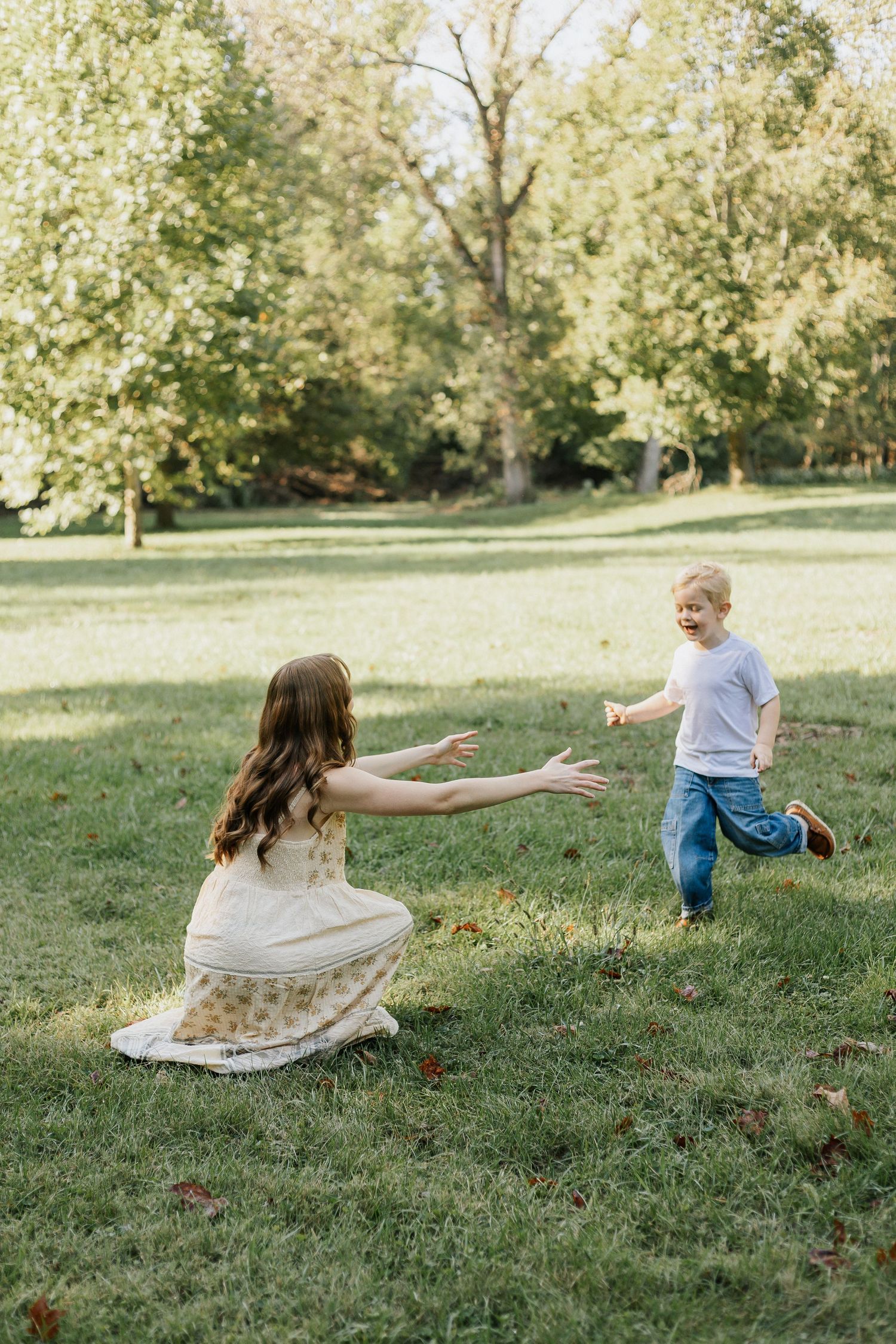 Heartwarming play scene in a green park with arms outstretched for embrace.