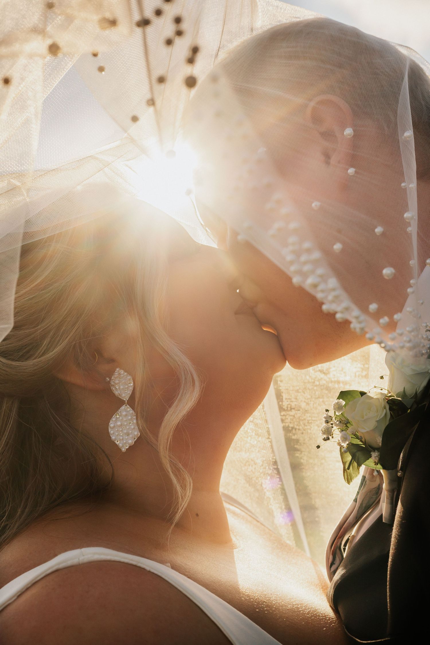 Sunlit wedding veil detail shot with delicate lace and sparkling details.
