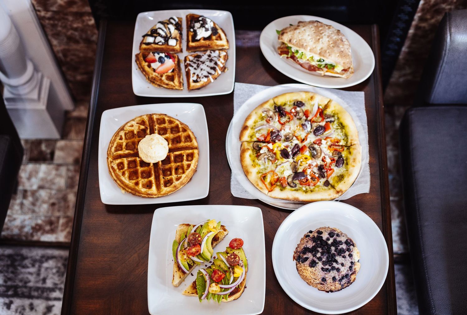 Overhead view of waffles and pizzas arranged on white plates.