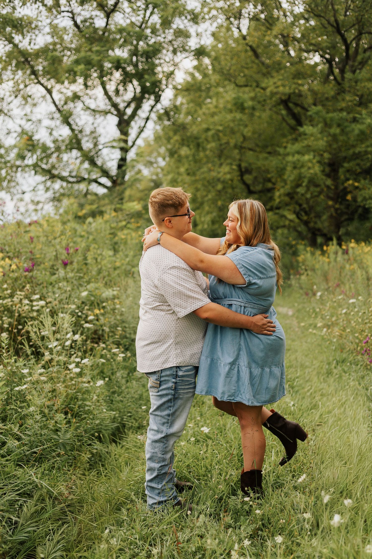 Romantic embrace in wildflower meadow during summer photoshoot.