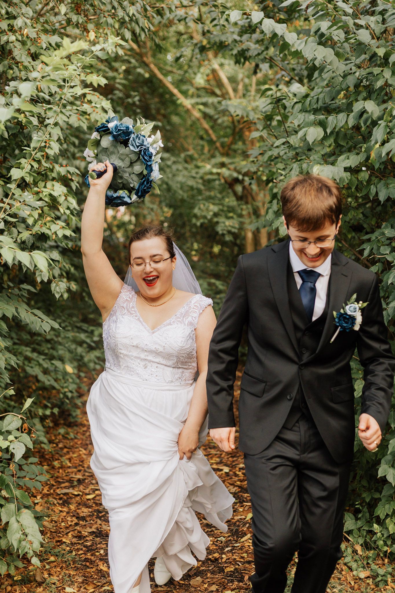 Joyful couple celebrating while walking through a leafy garden path.