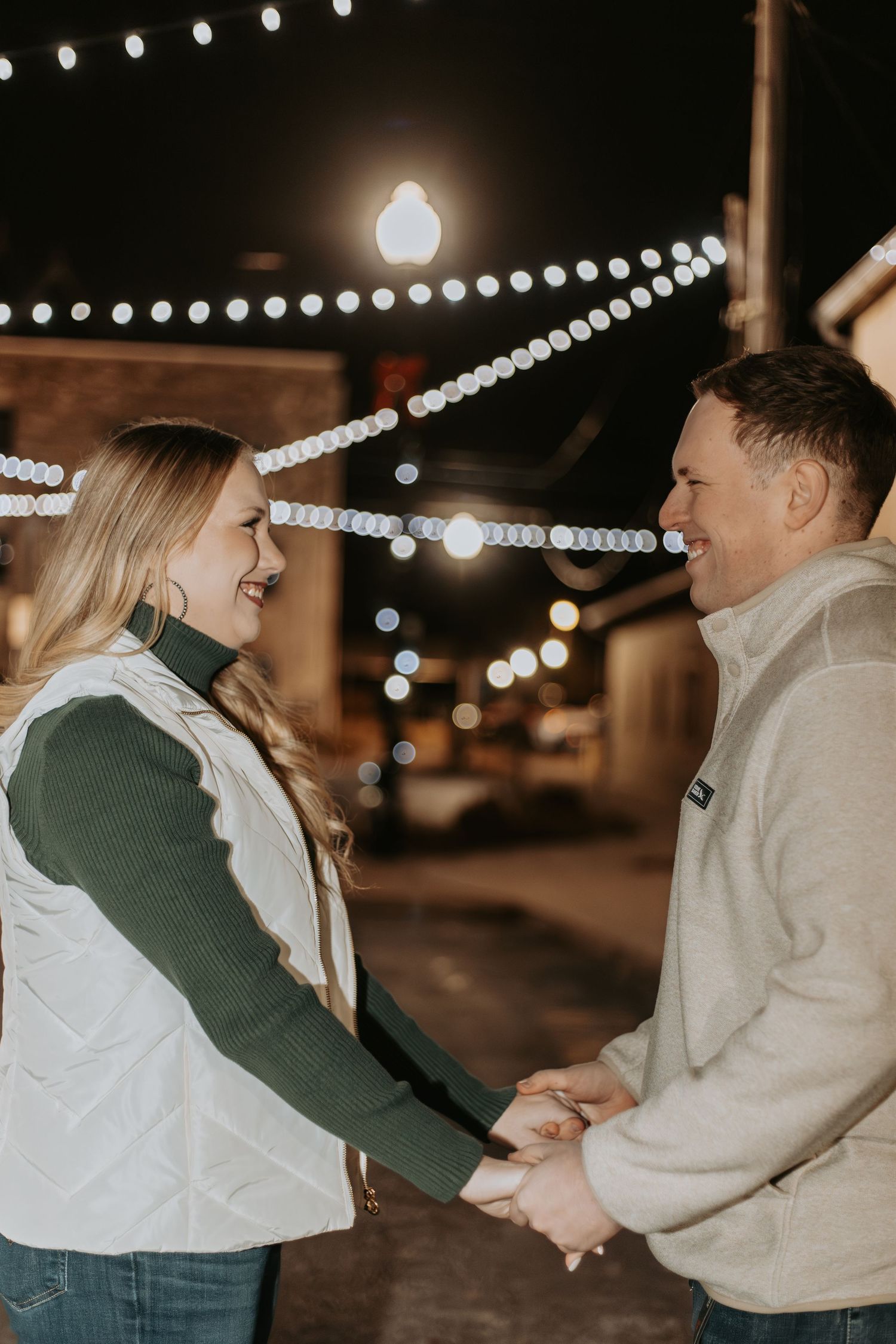 Couple sharing a romantic moment under twinkling string lights on a cozy evening.