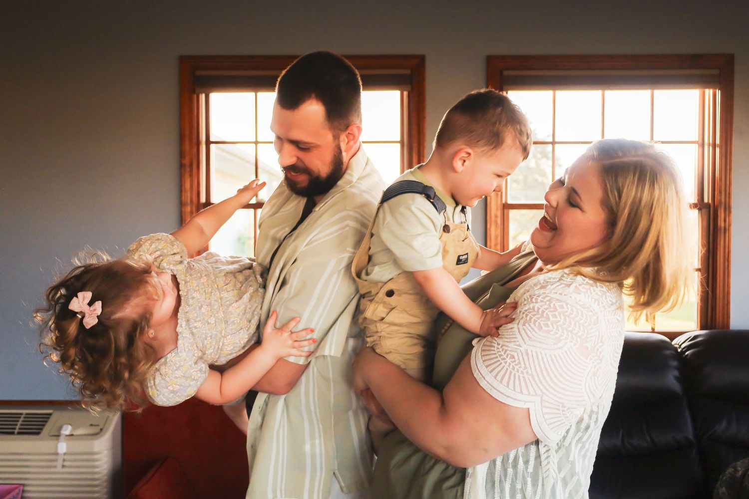 A tender family moment captured in warm indoor lighting near windows.