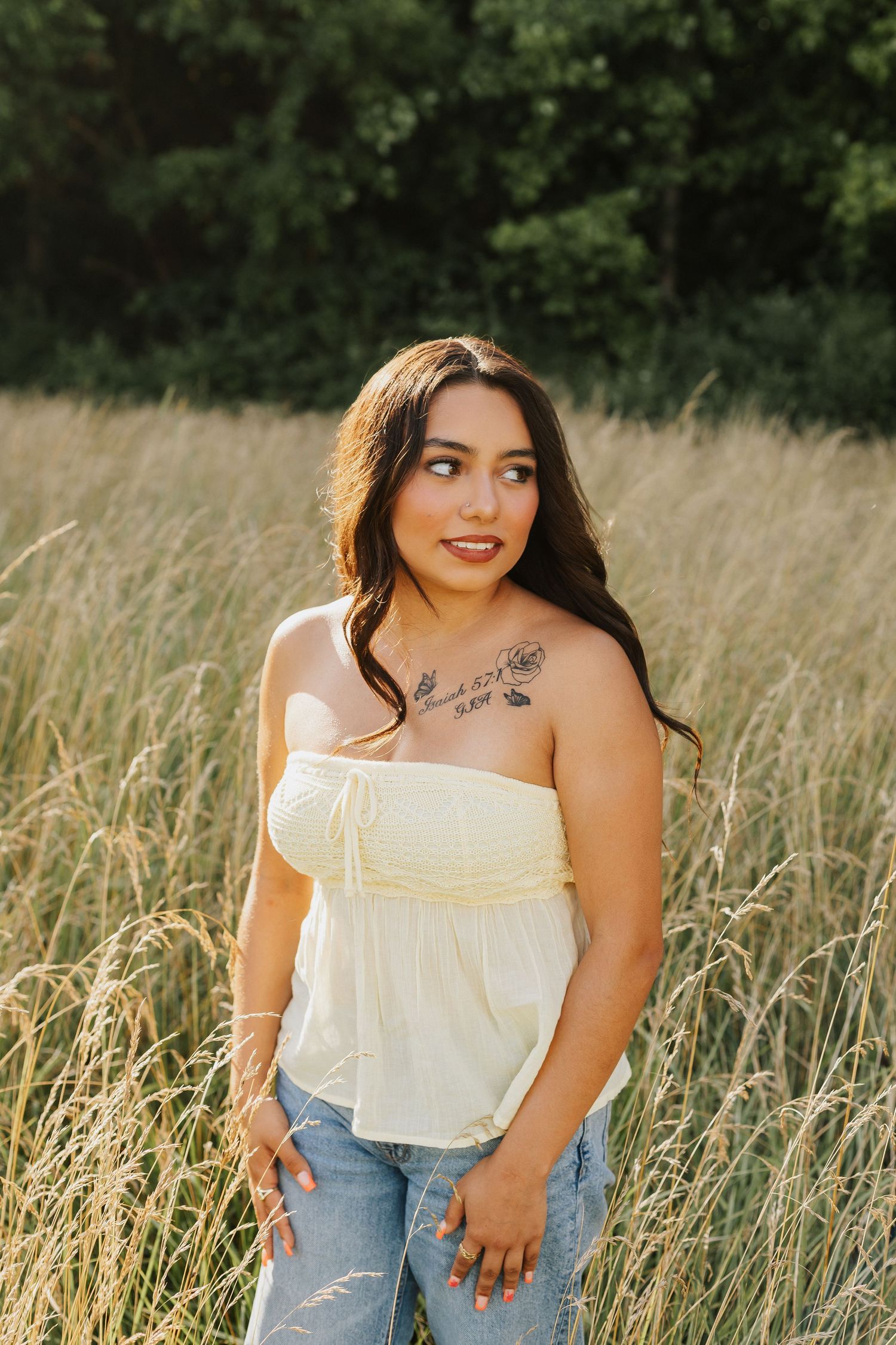 Summer portraits in a field with tall grass wearing cream top and jeans.