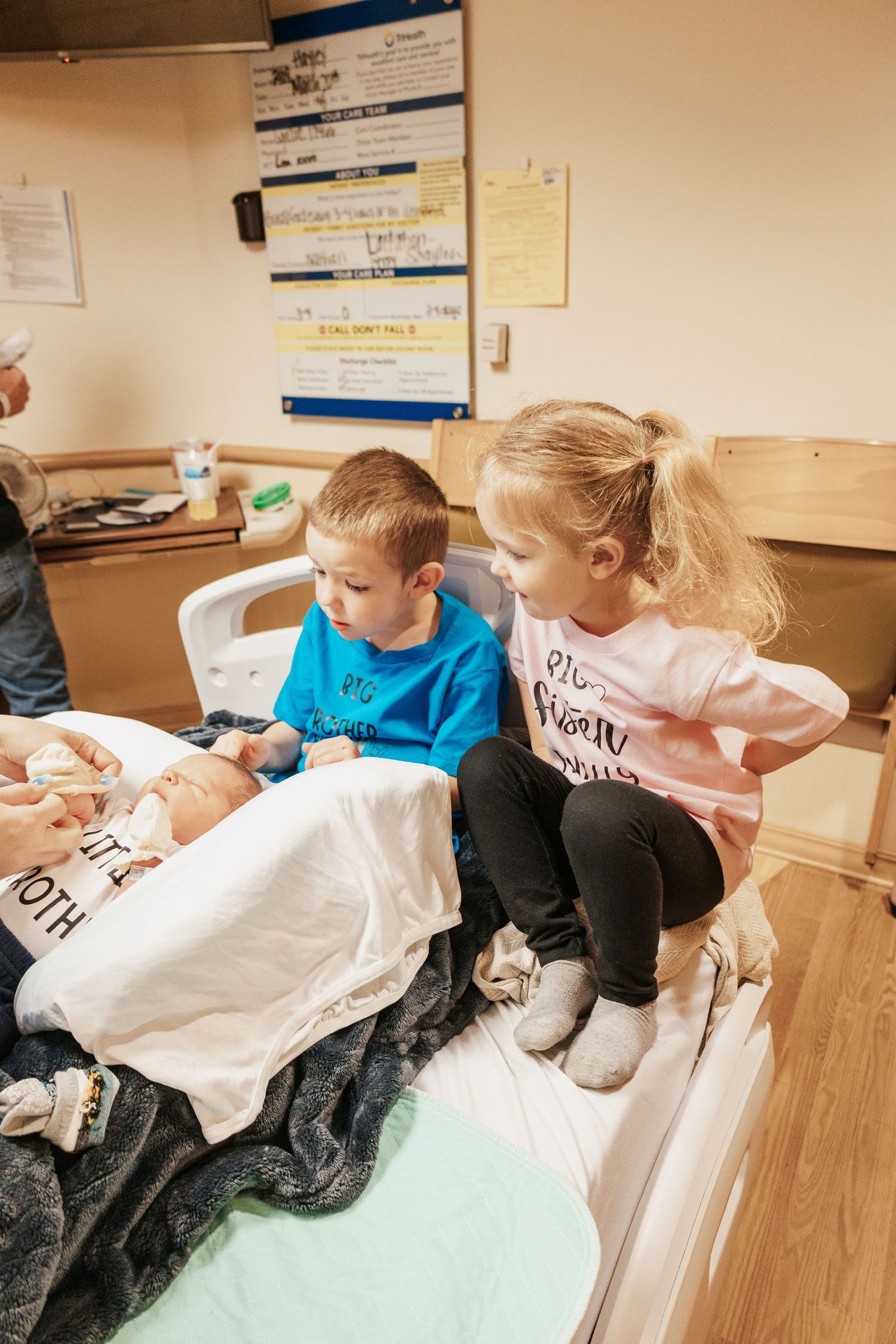 Children in matching shirts sitting together in medical office chairs.