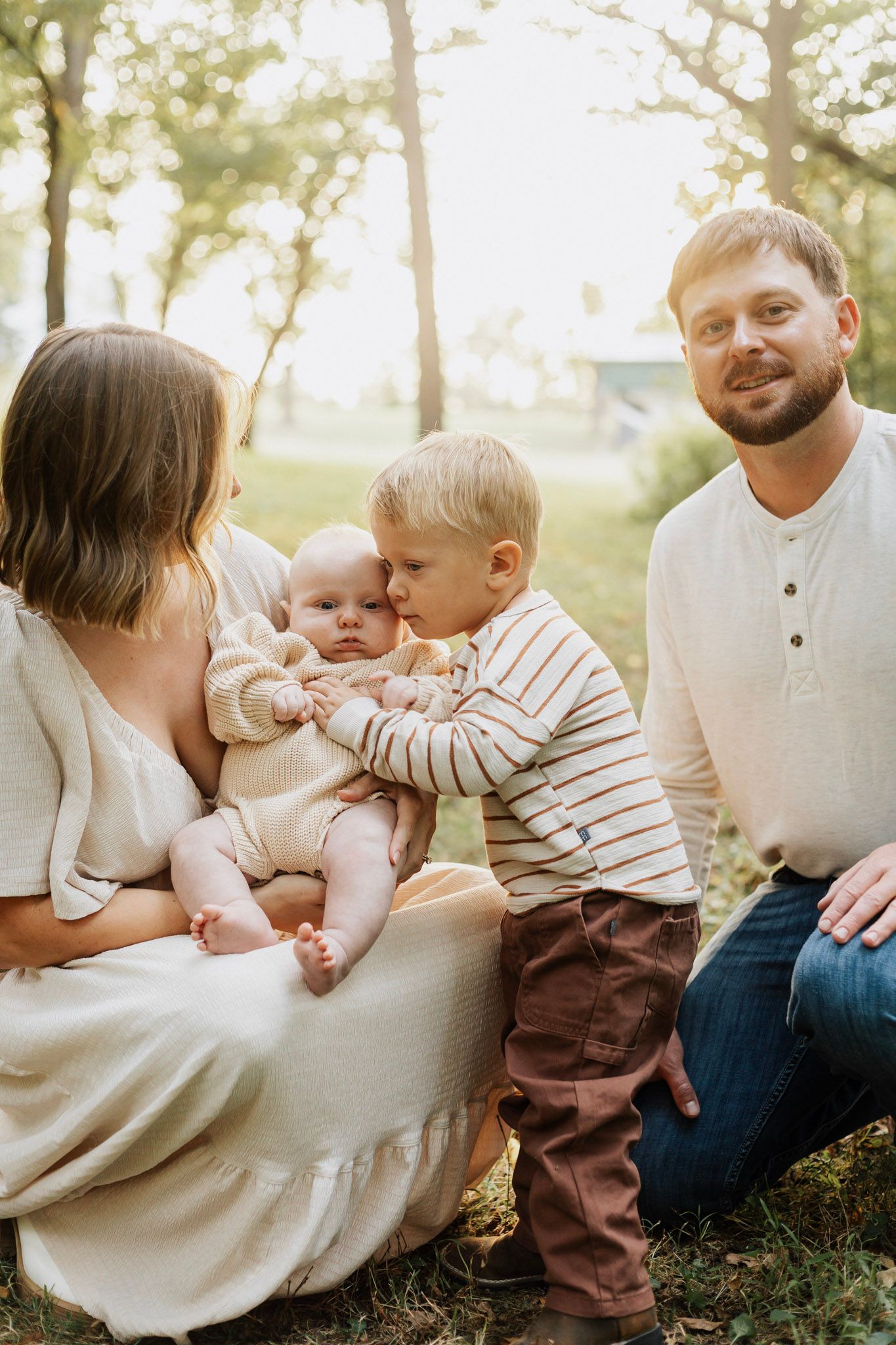 Family sitting together outdoors during golden hour sharing tender moments.