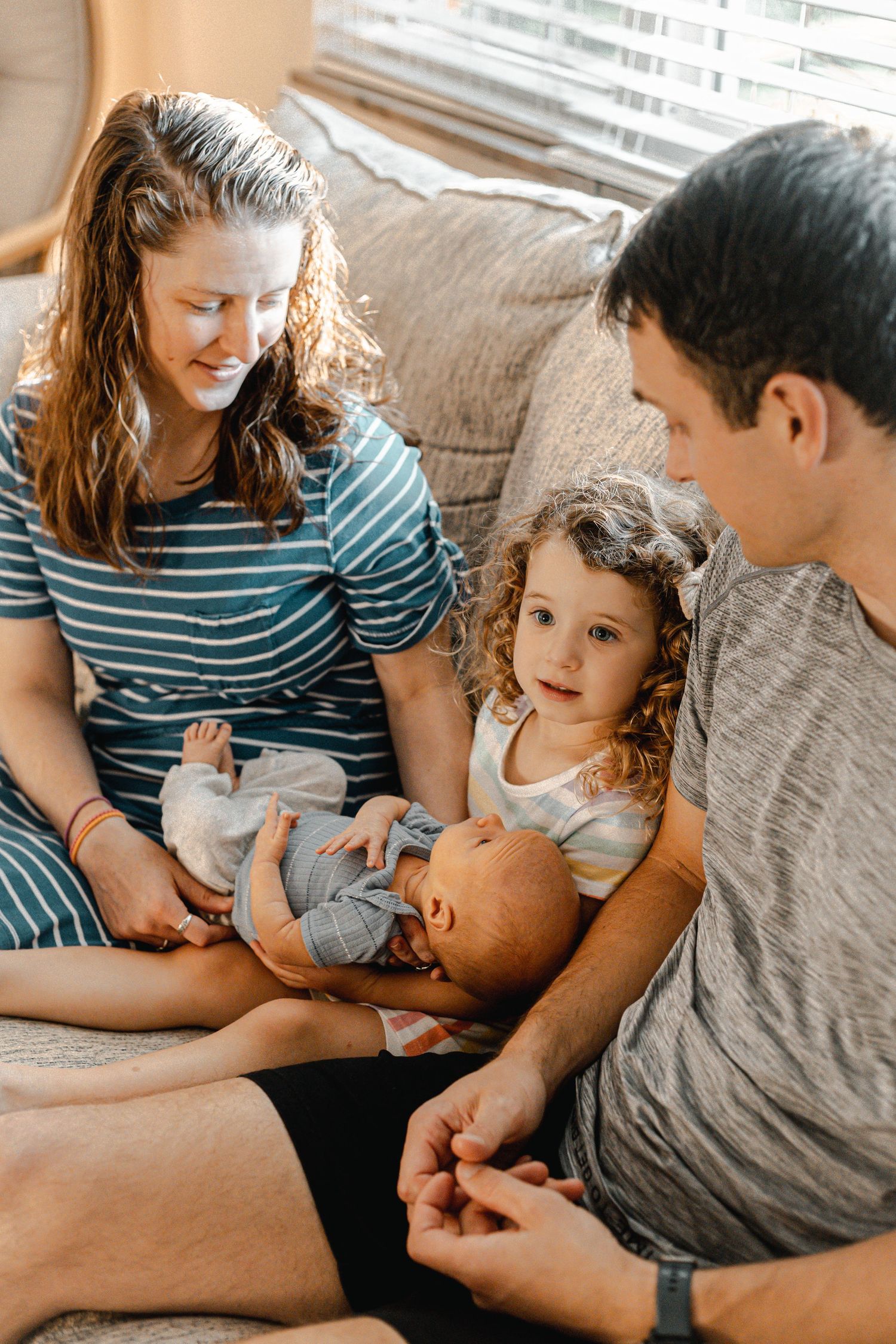 Intimate family moment captured on couch with soft window light.