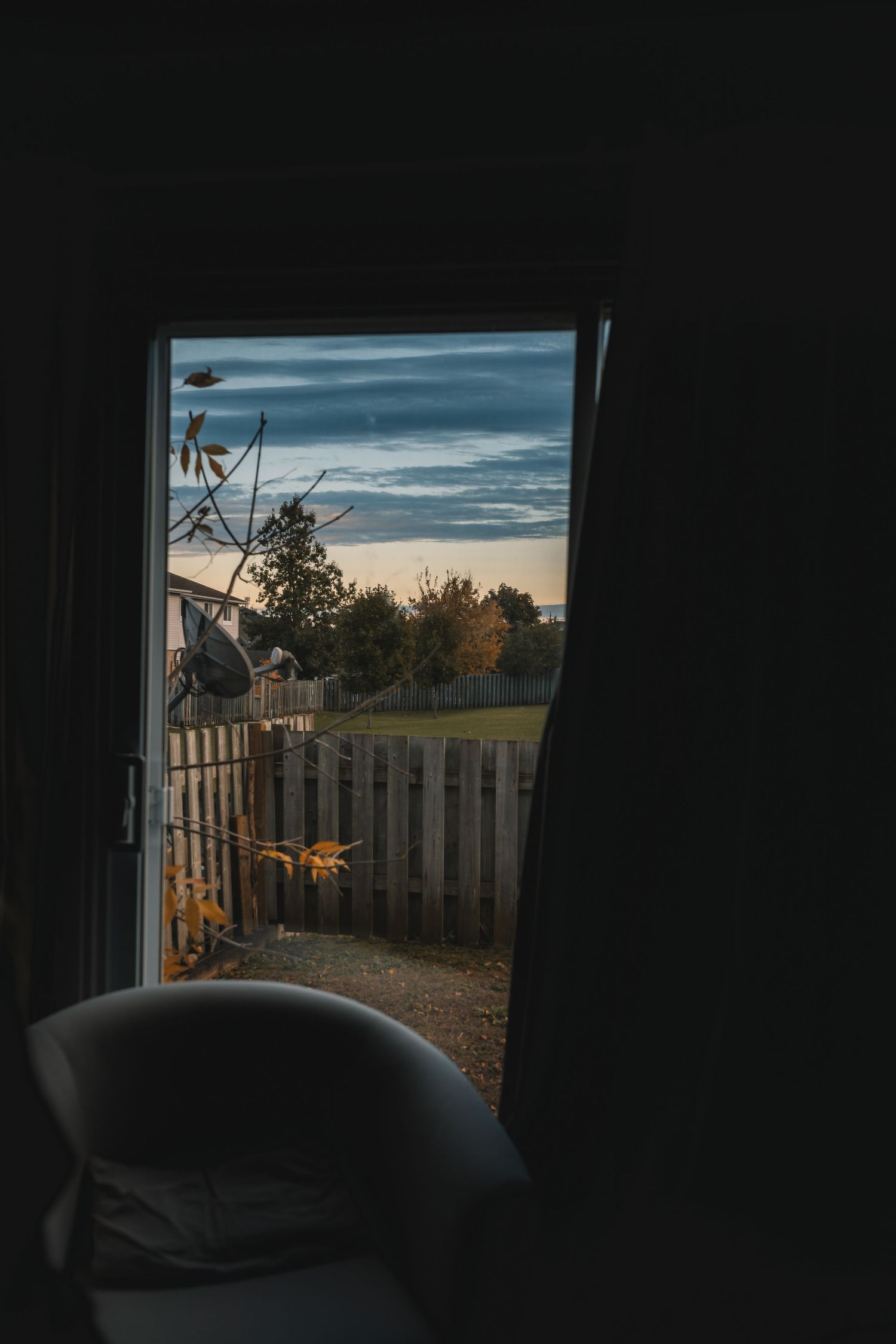 View through dark doorway of sunset over backyard fence.