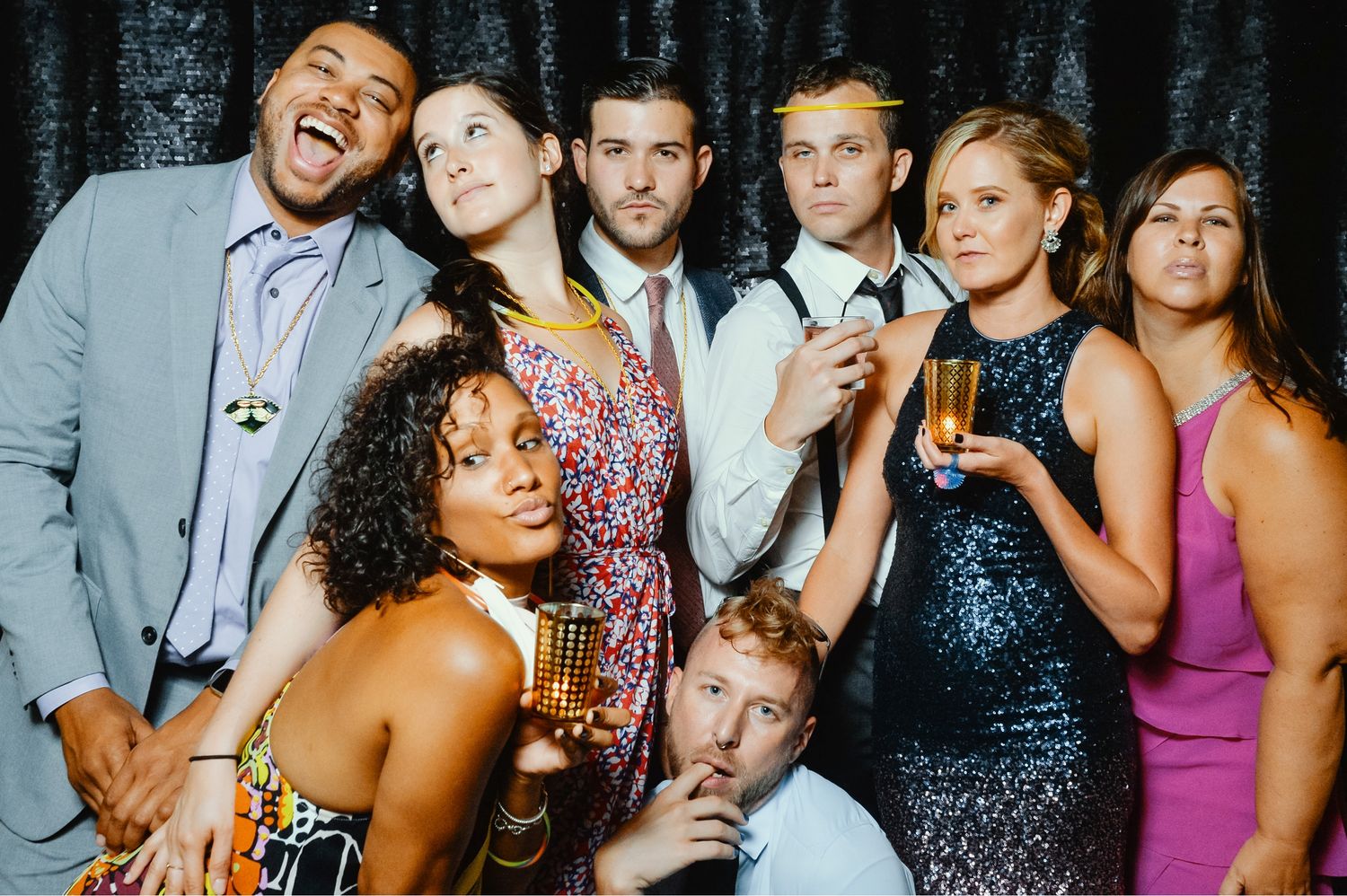 Group of friends posing in a photo booth at a festive party, dressed in elegant attire and accessories.